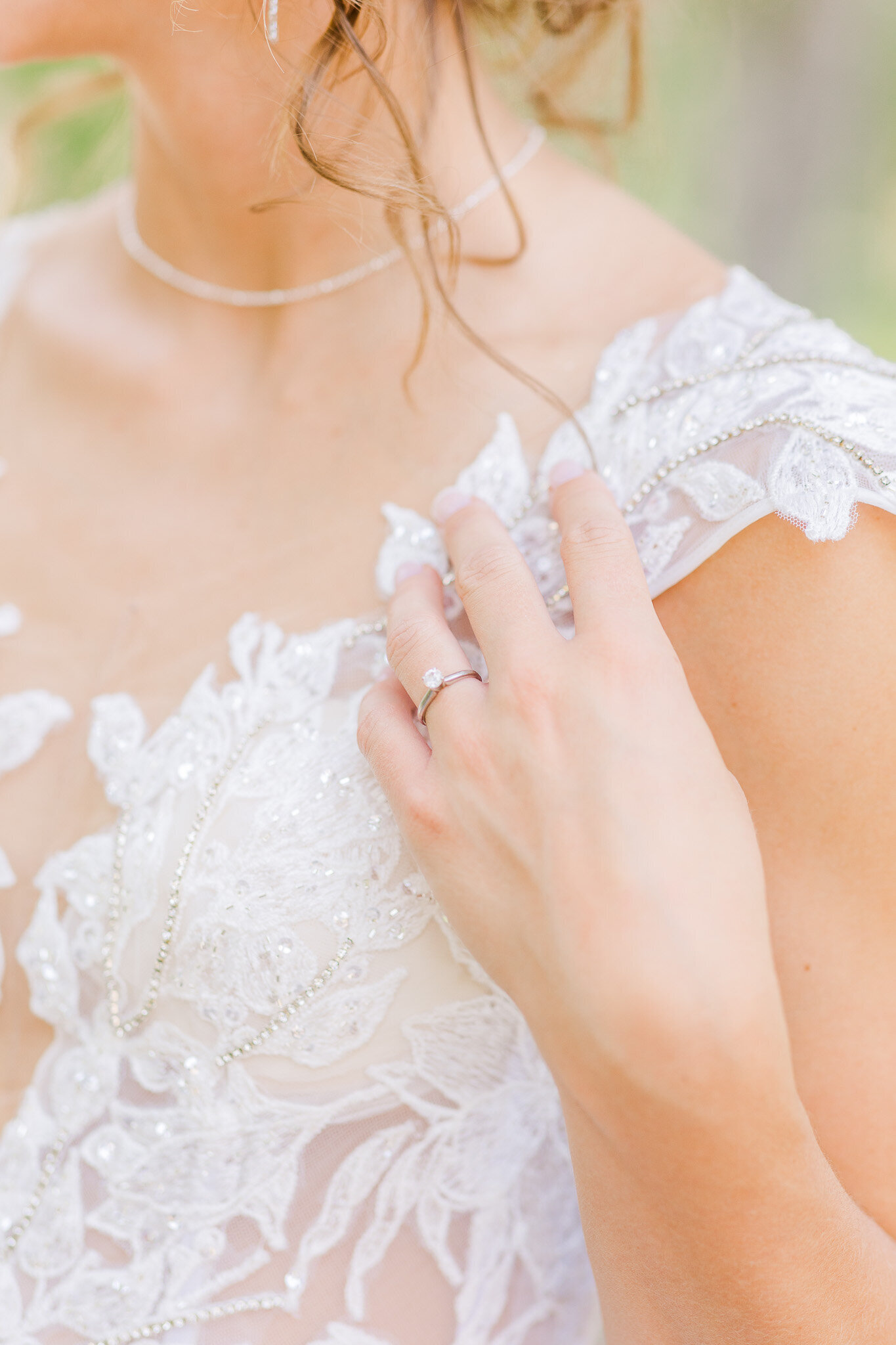 Up close of engagement ring on bride in gown