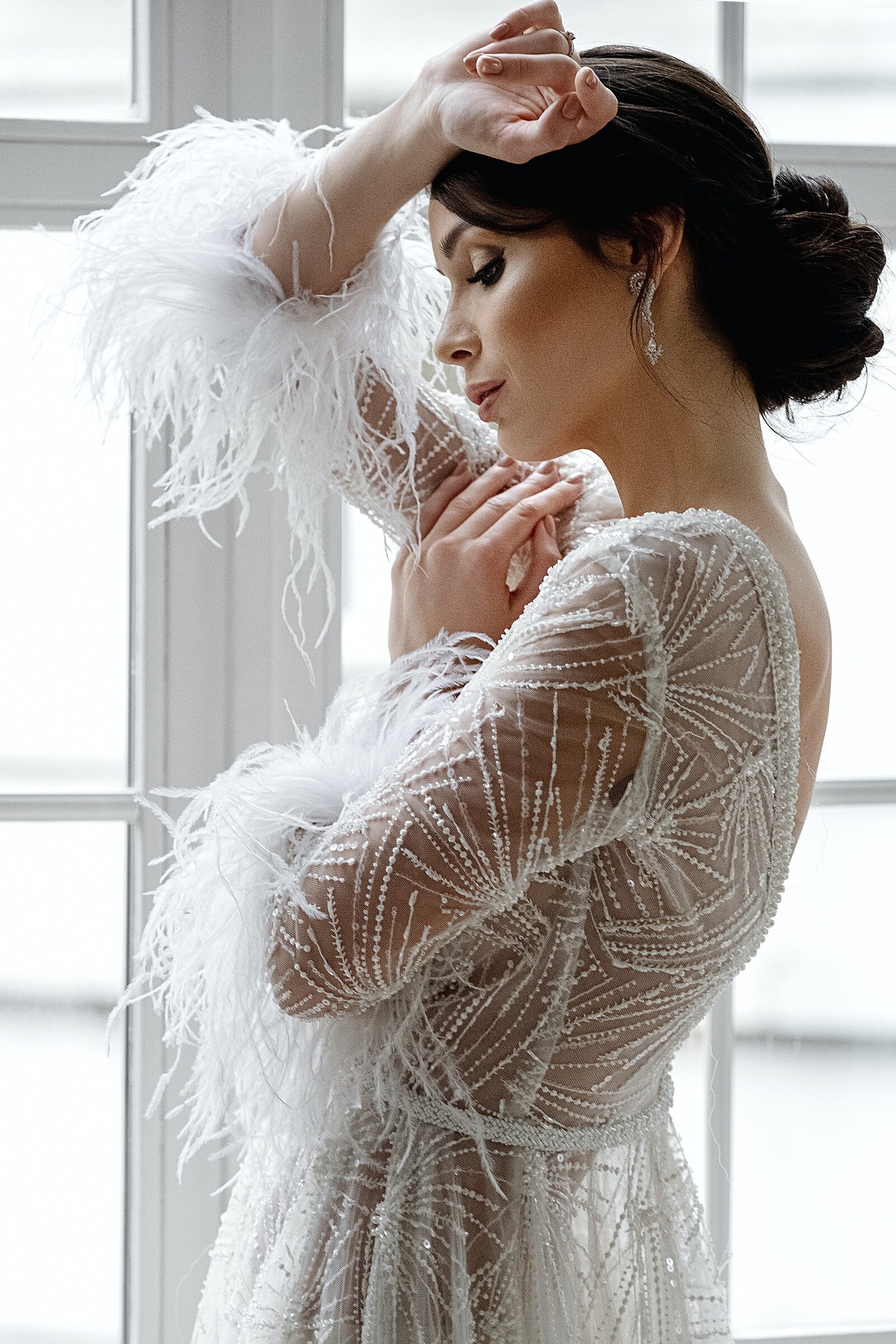 bride wearing white beaded wedding dress with feathers