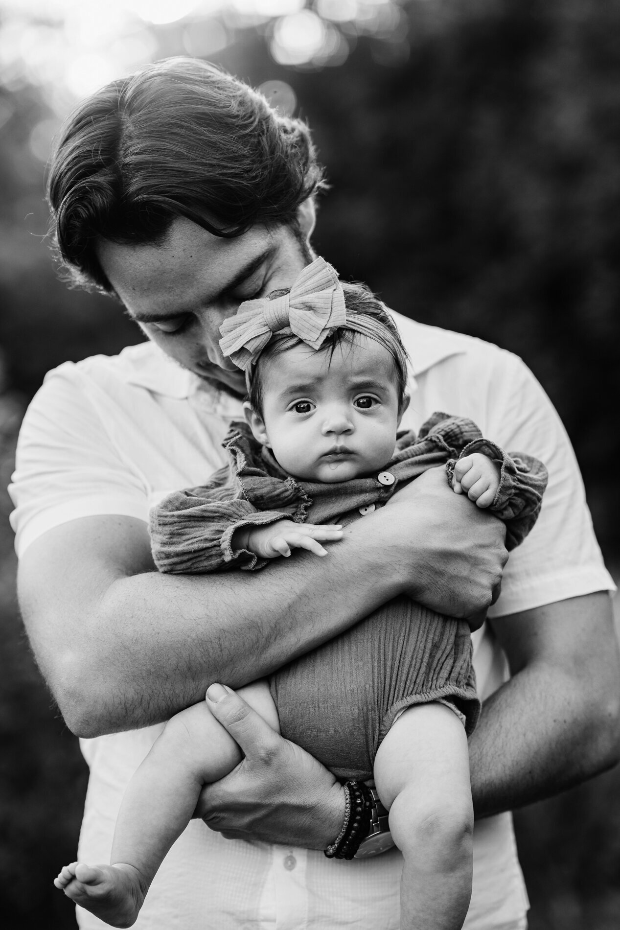 father holds infant daughter outdoors at sunset