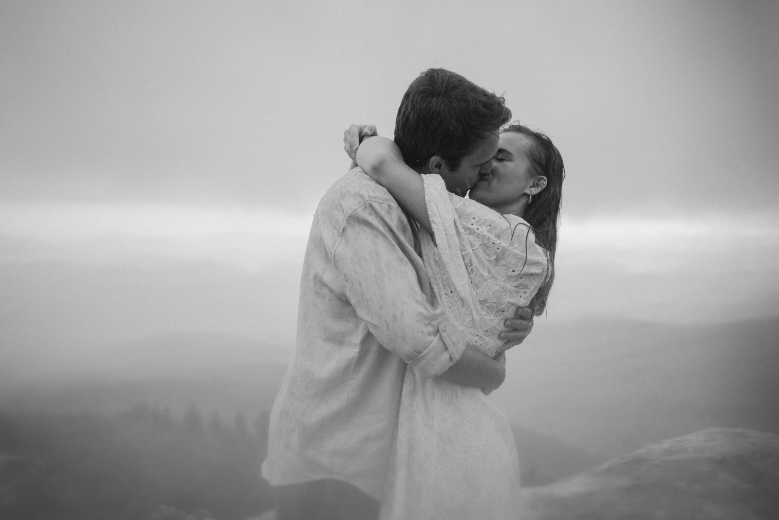 An engaged couple kisses in the rain in the Great Smoky Mountains near Asheville.