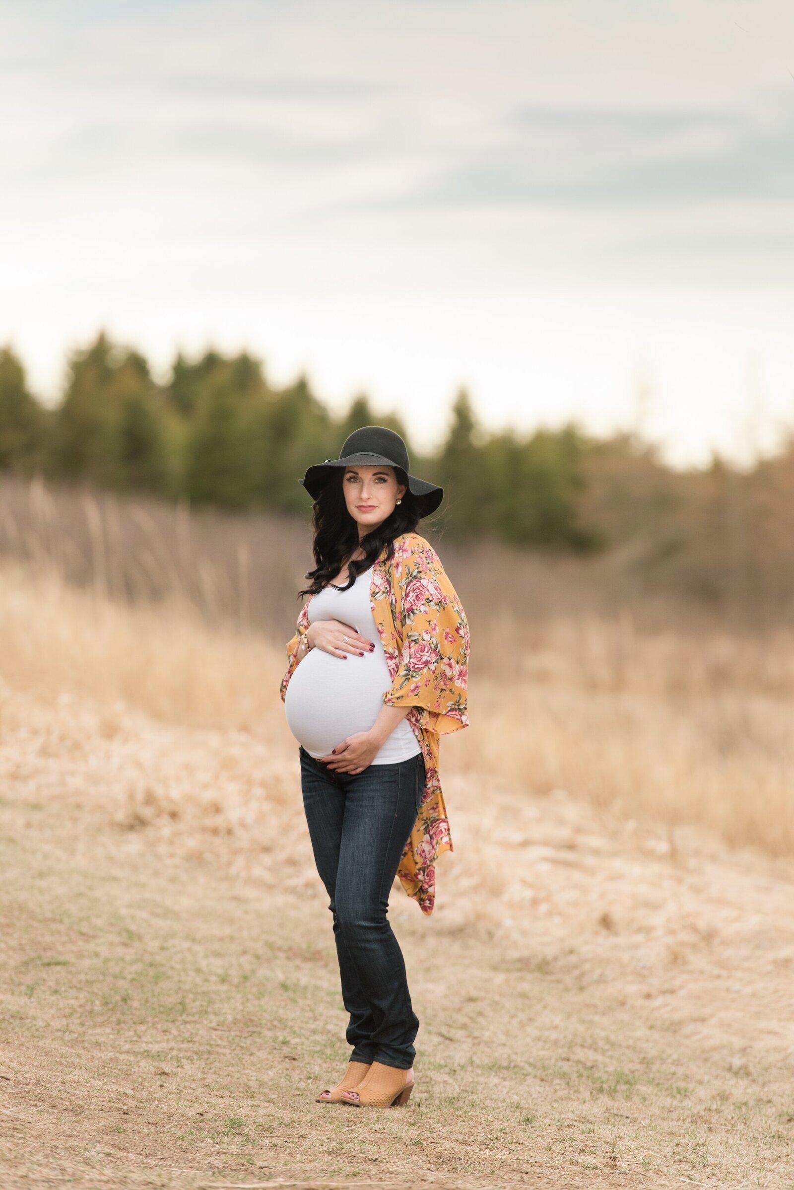 maternity session in the fall of a woman wearing a black hat and jeans