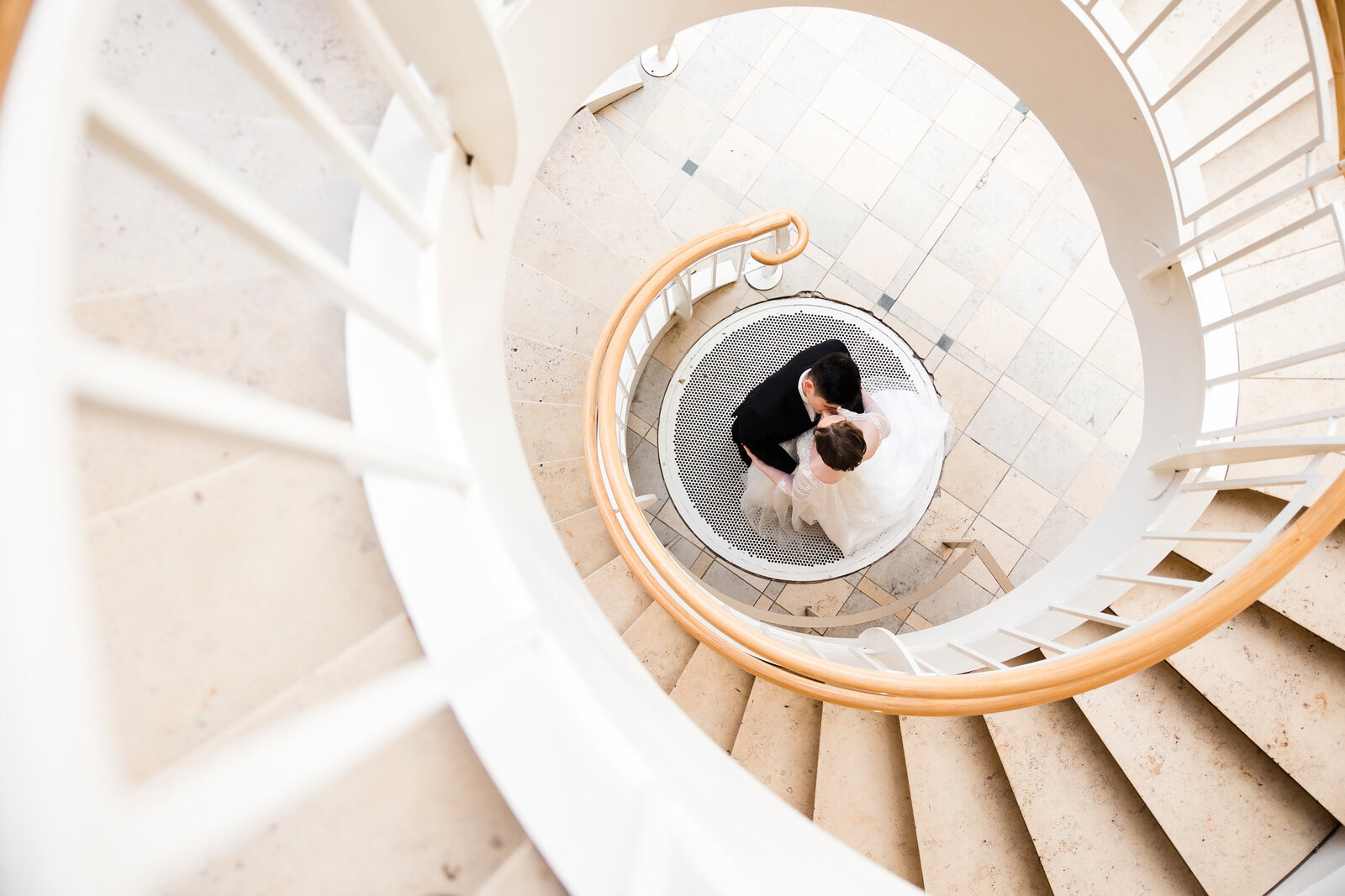A bride and groom standing on a spiral staircase at Fernbank Museum. Wedding photo taken by Gary Lun Photography