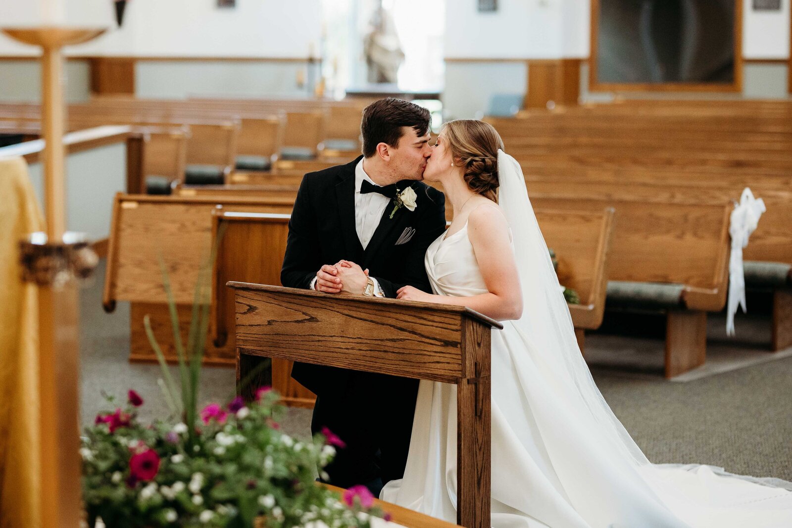 Couple kneeling at the alter, share a passionate kiss