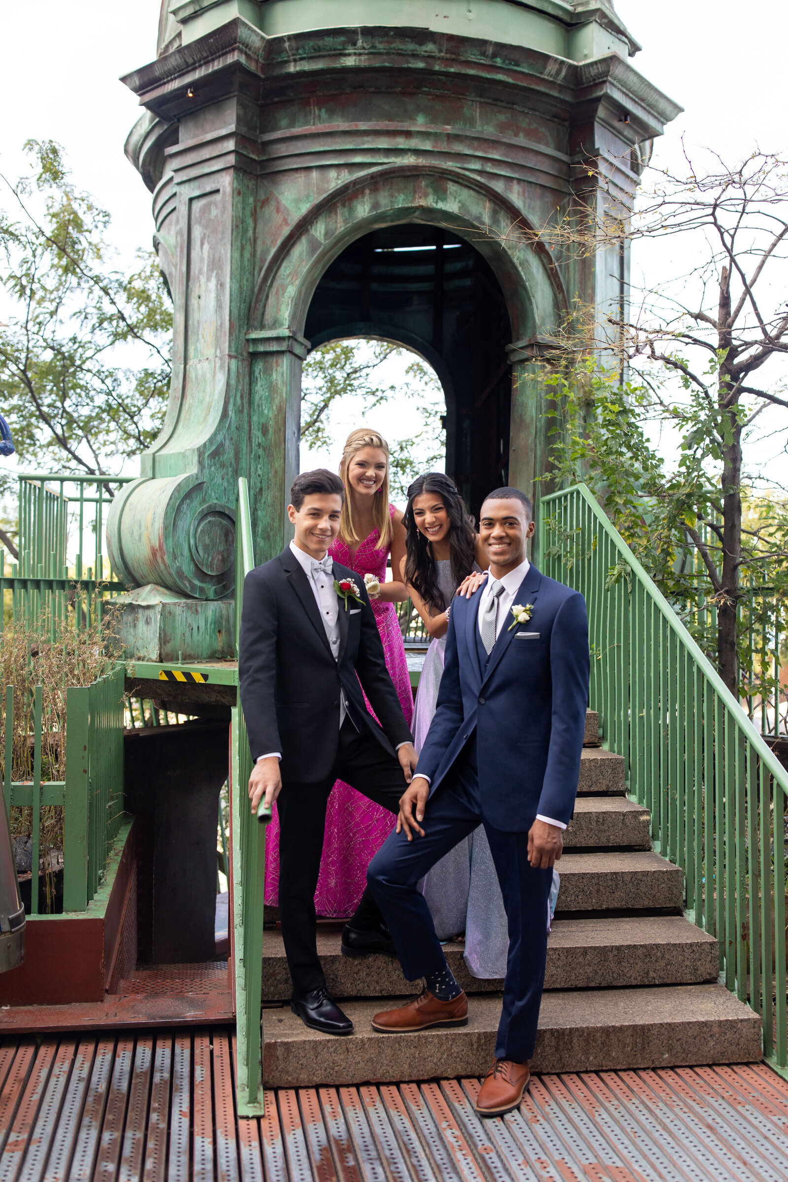 Group of well-dressed friends posing together on outdoor stairs at a formal event