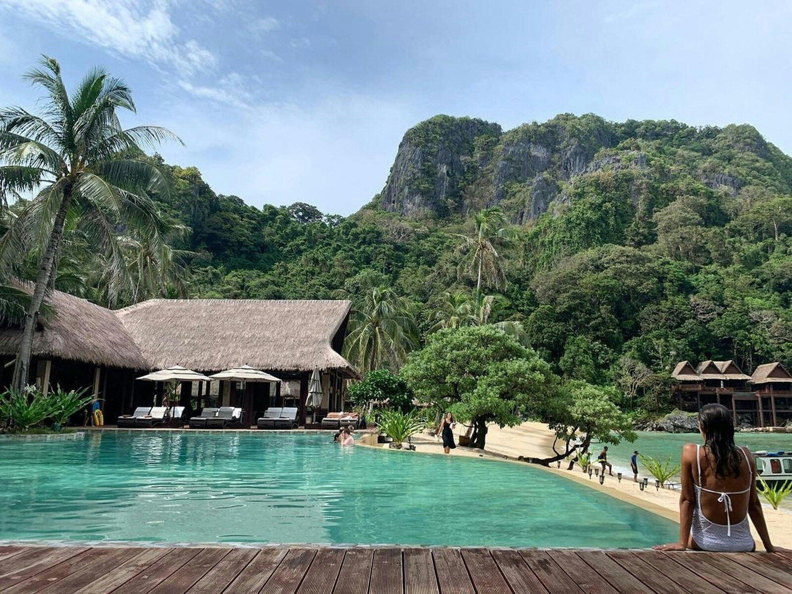 Woman sitting down the poolside with a beautiful nature and mountain view
