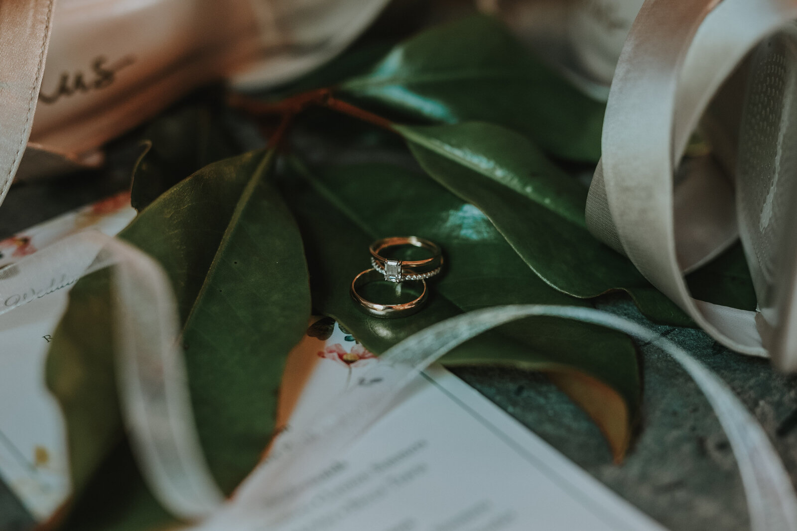 Shoes and wedding rings sit on top of a large leaf