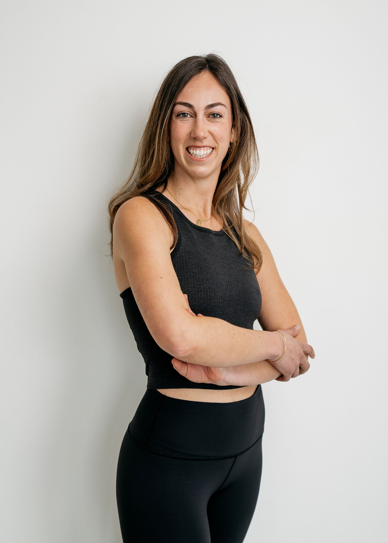 A member in black activewear standing with arms crossed