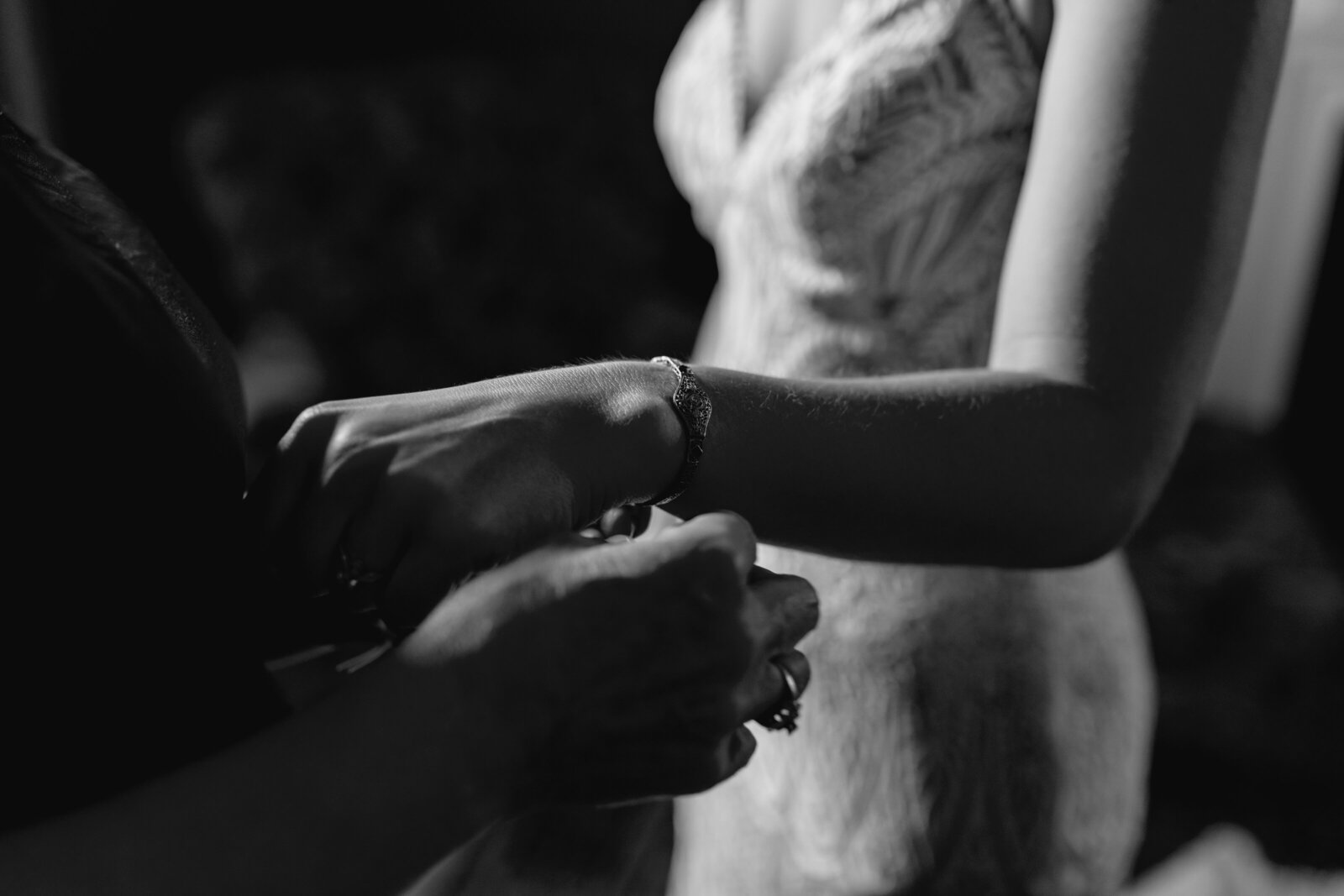 A mother puts on her daughter's bracelet as she puts on her wedding dress