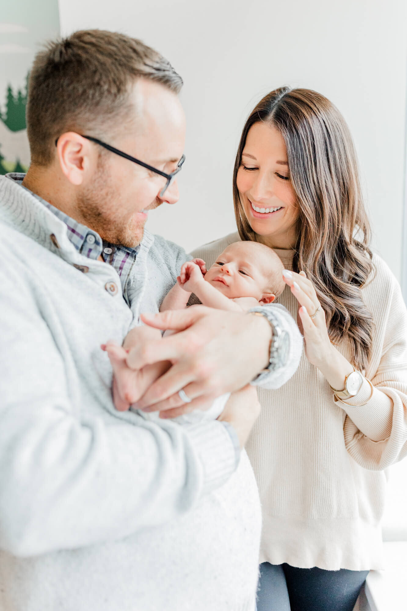 Dad standing and holding newborn while mom smiles and looks on at Boston Children's Hospital