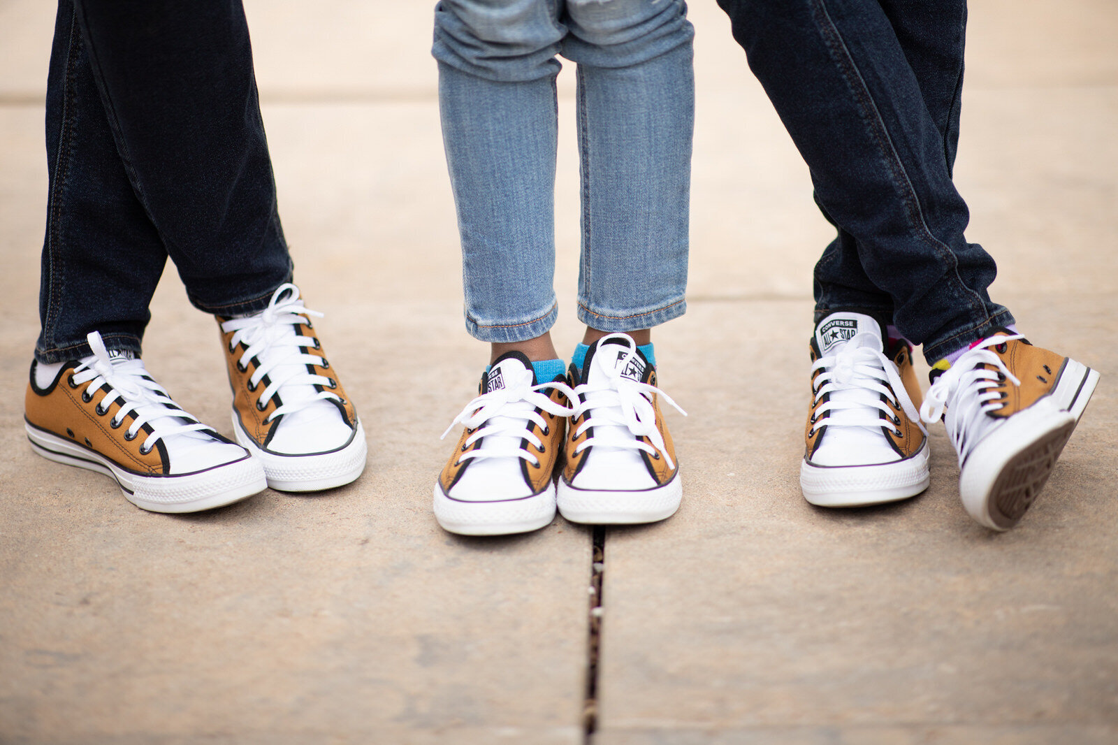 three brown all star converse shoes on the sidewalk