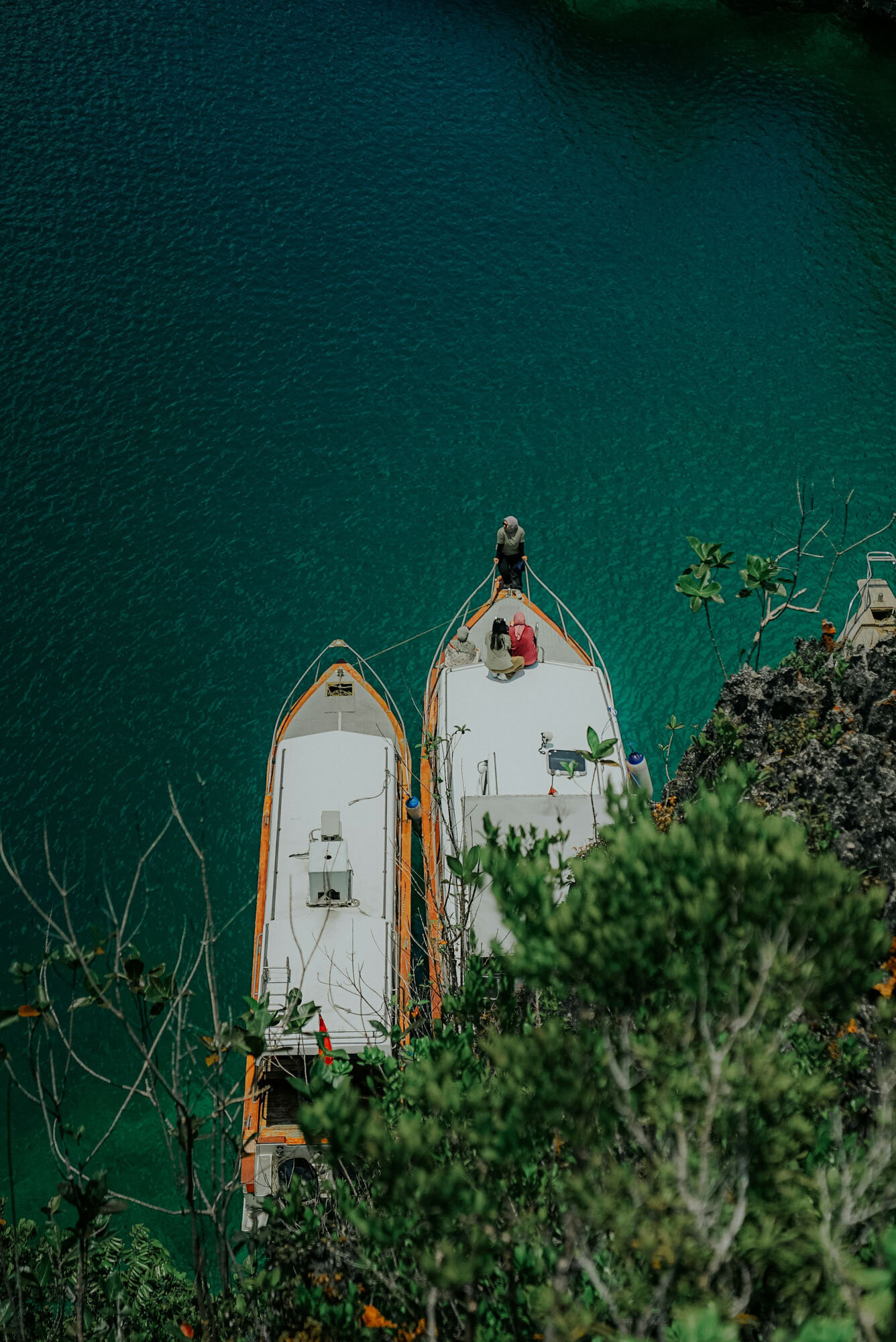 Two boats are tied to a cliff overlooking a body of water