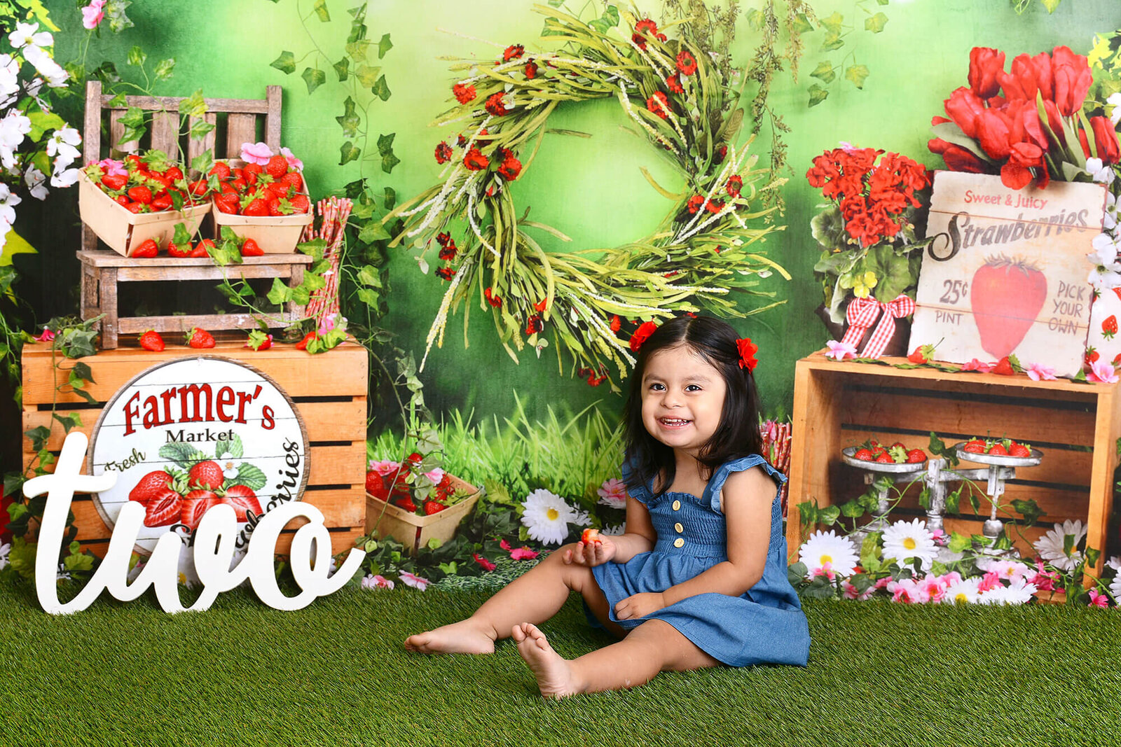 girl smiles at her strawberry themed second birthday photoshoot in houston
