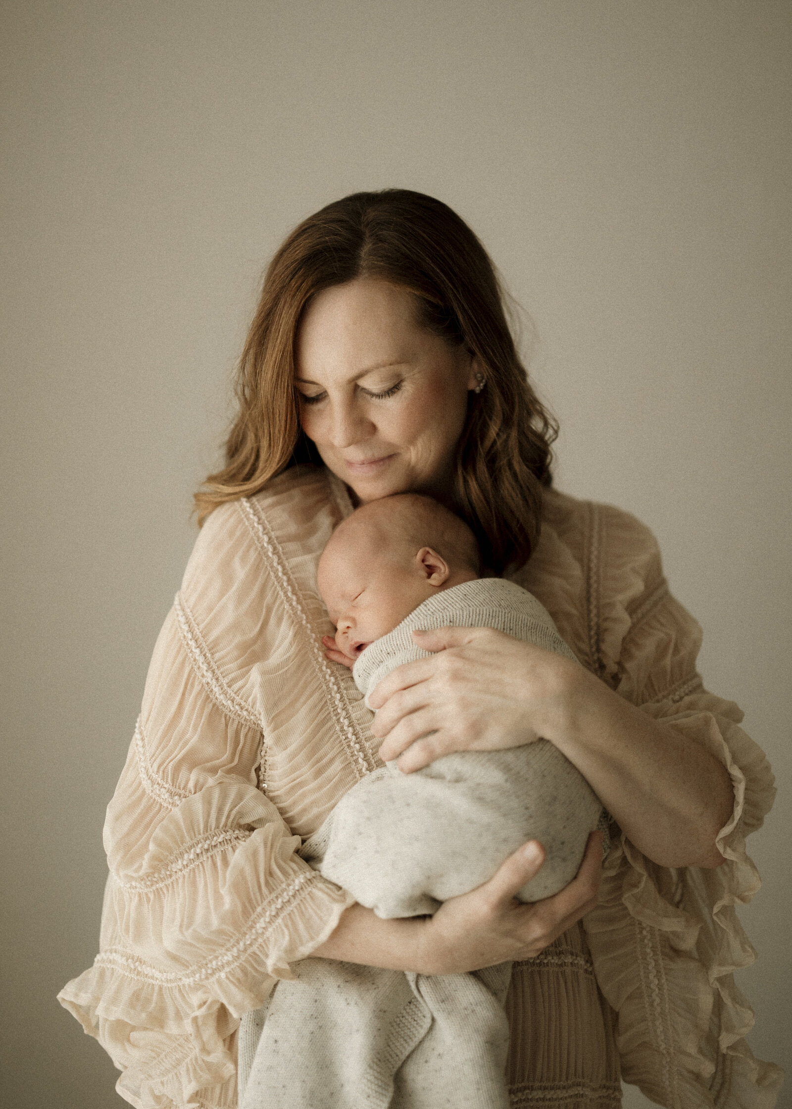 Studio newborn family photography in Perth – a beautiful, intimate portrait of new parents holding their baby in soft natural light.