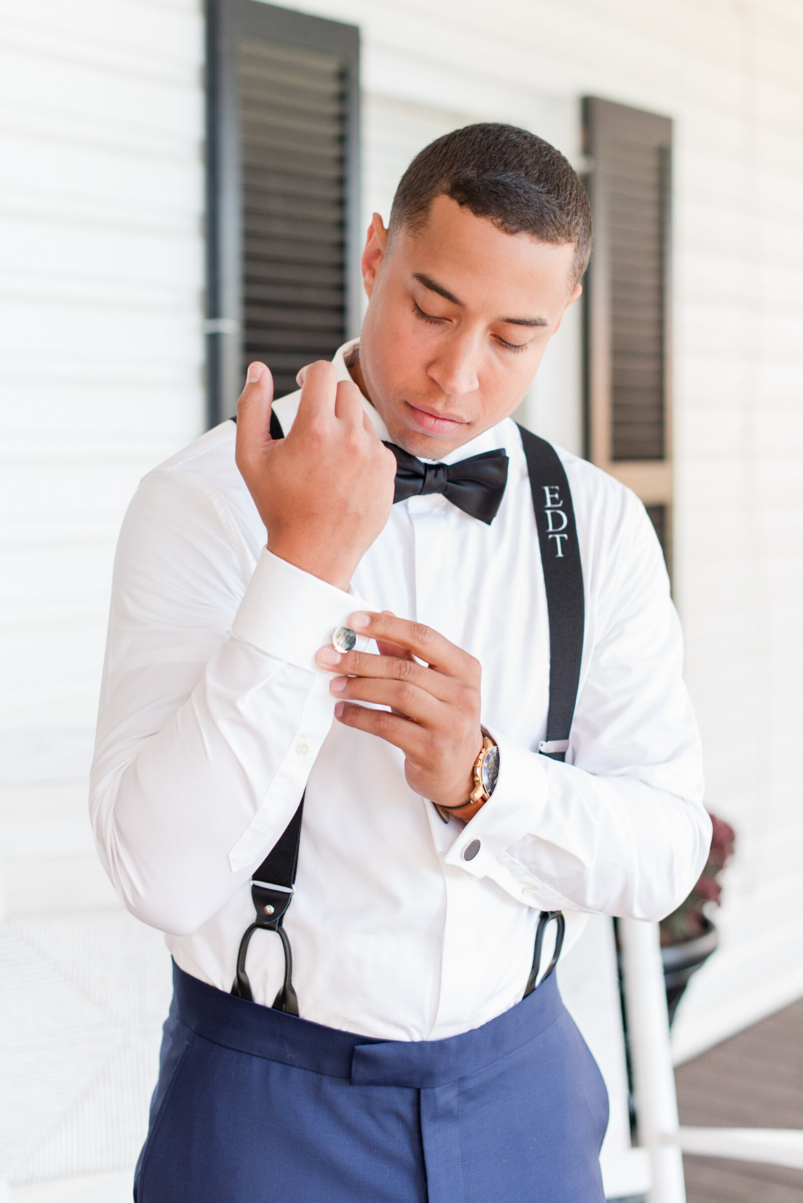 groom getting ready on wedding day blue tuxedo engraved suspenders bowtie