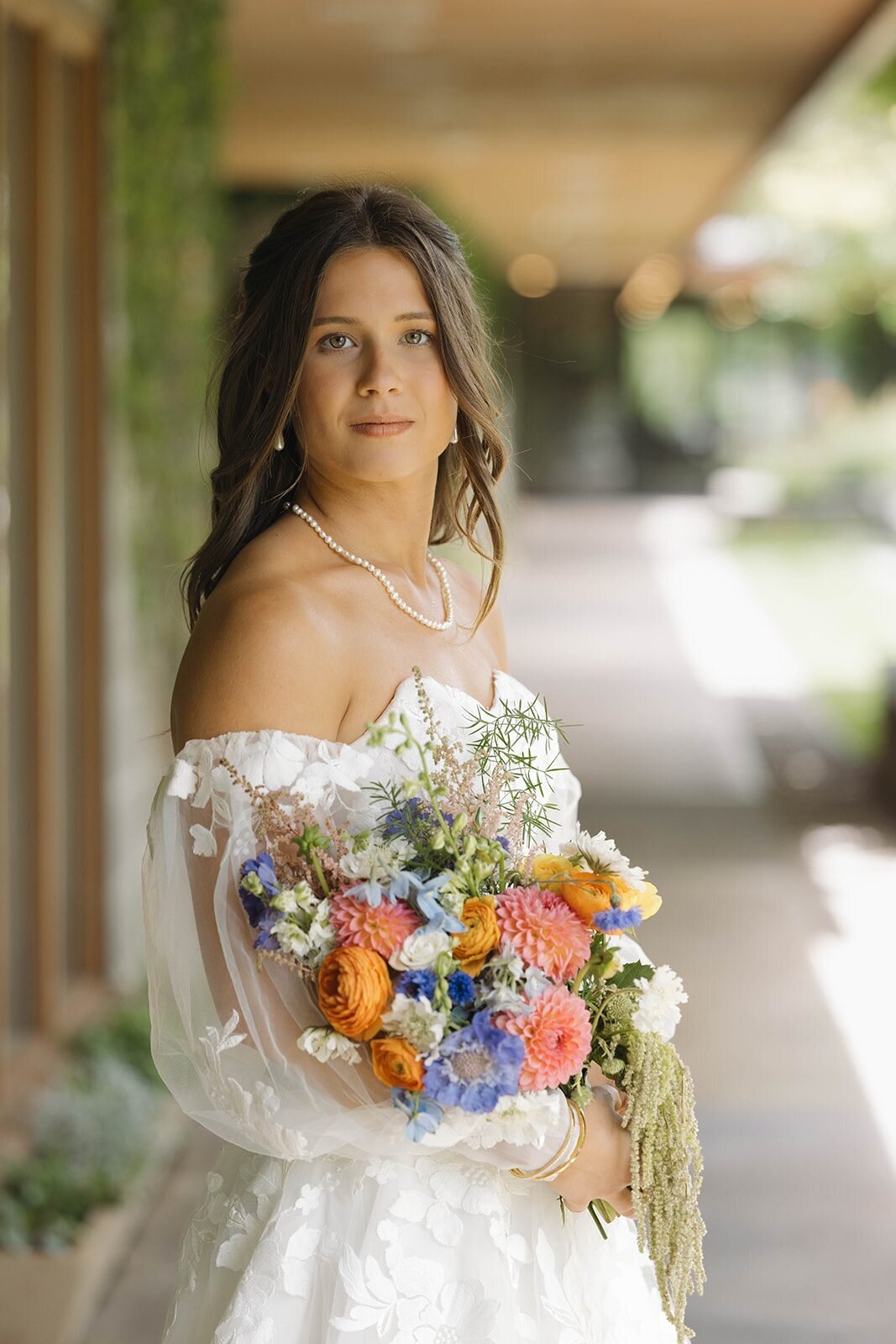 Bride holding her colorful bouquet on the covered walkway