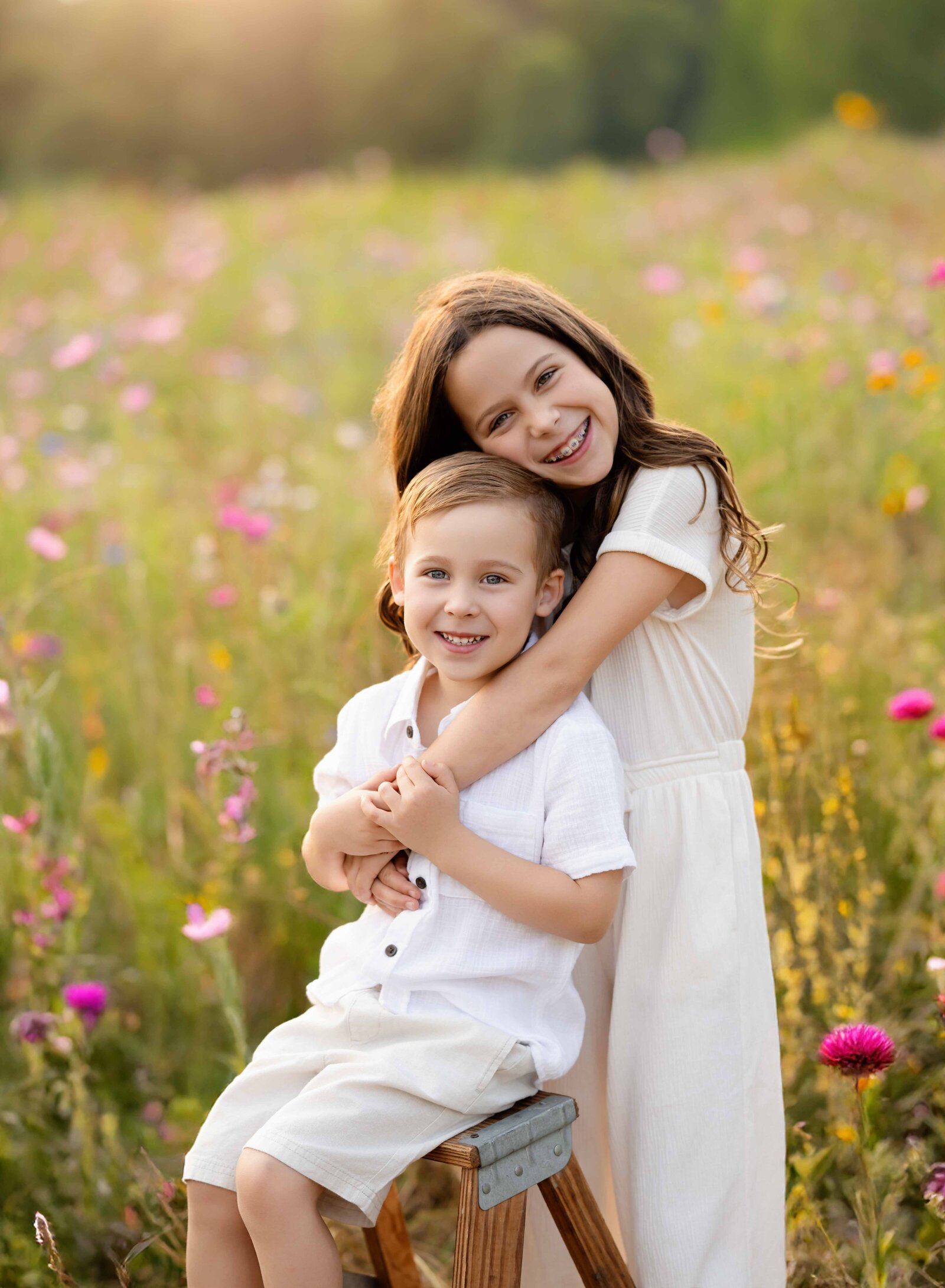 Sister hugging brother in a wildflower field and smiling at camera. Wildflower field in Lawrenceville, GA close to Atlanta.