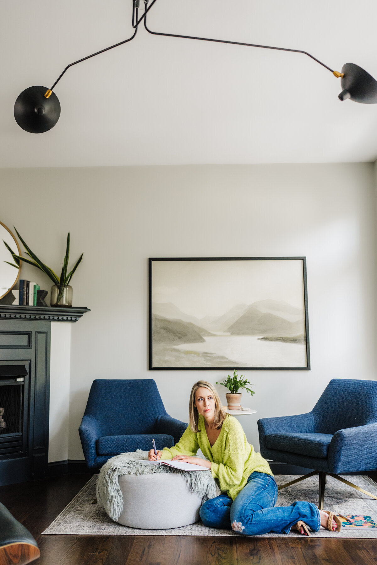 woman in lime green shirt sits in modern boston living room writing on pad