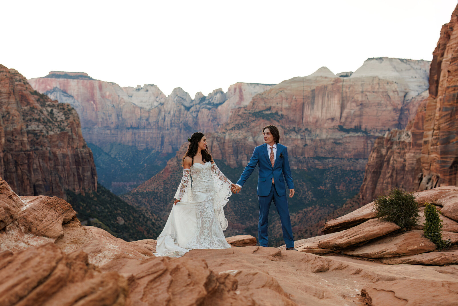 A bride and groom holding hands at the Zion Canyon overlook after their Zion National Park elopement.