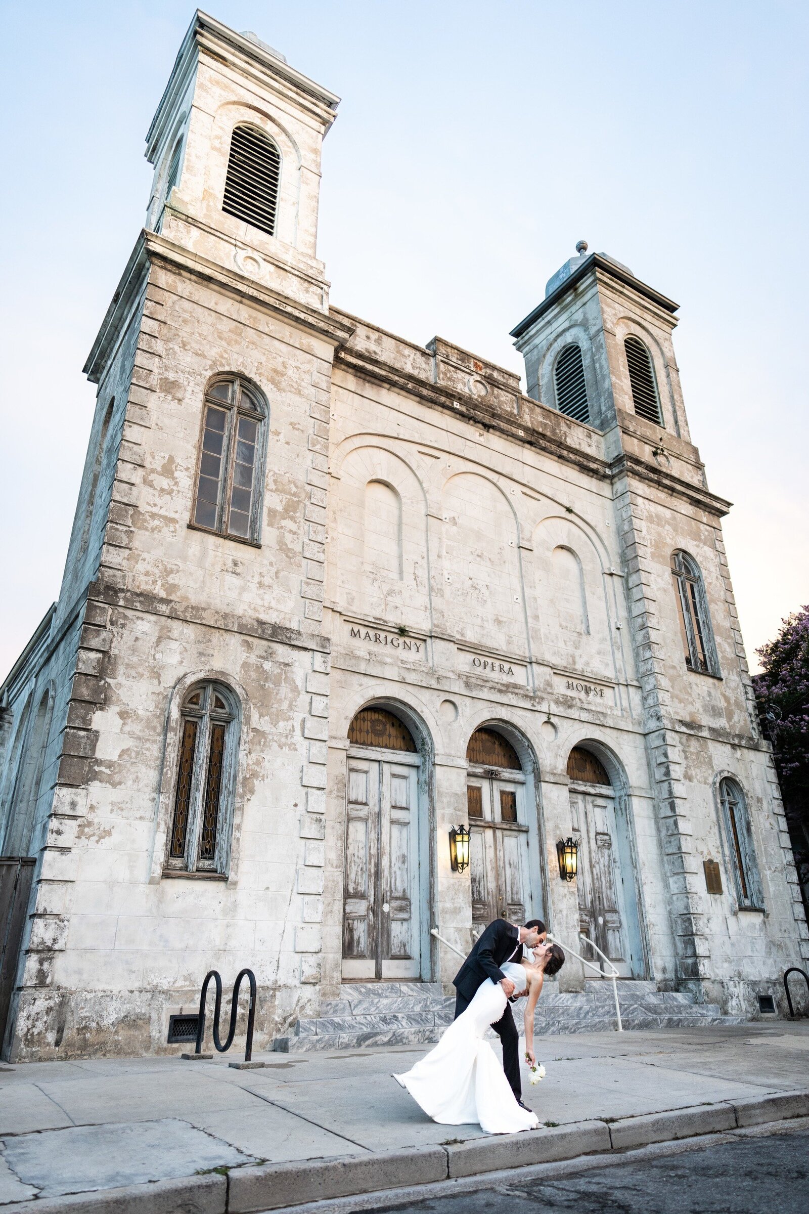 Bride and groom kiss in front of Marigny Opera House