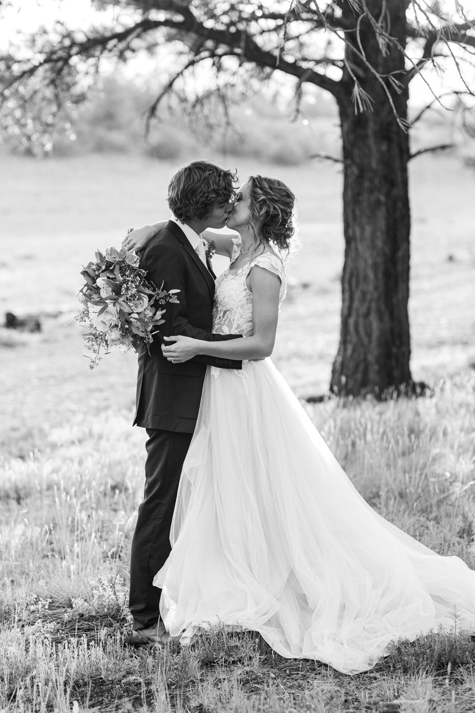 bride and groom black and white image share a kiss under a tree