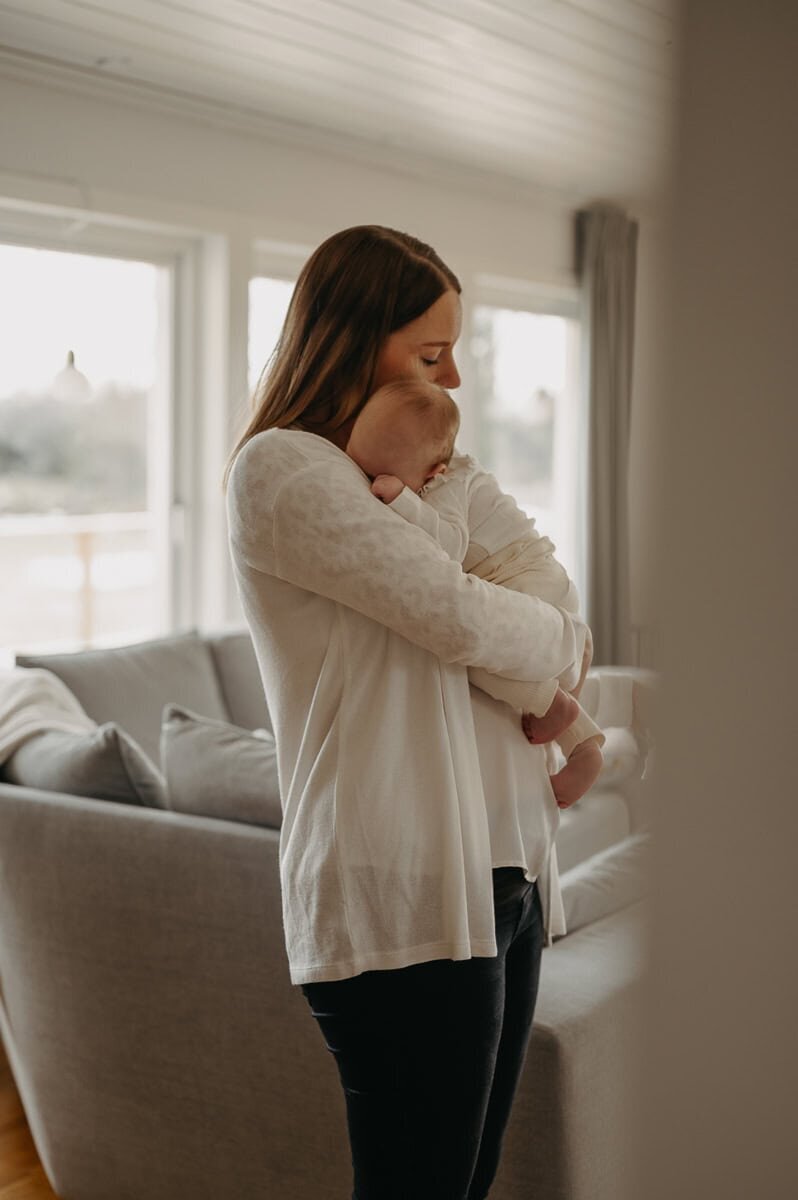 Mamman håller sin bebis i famnen som sover lugnt.