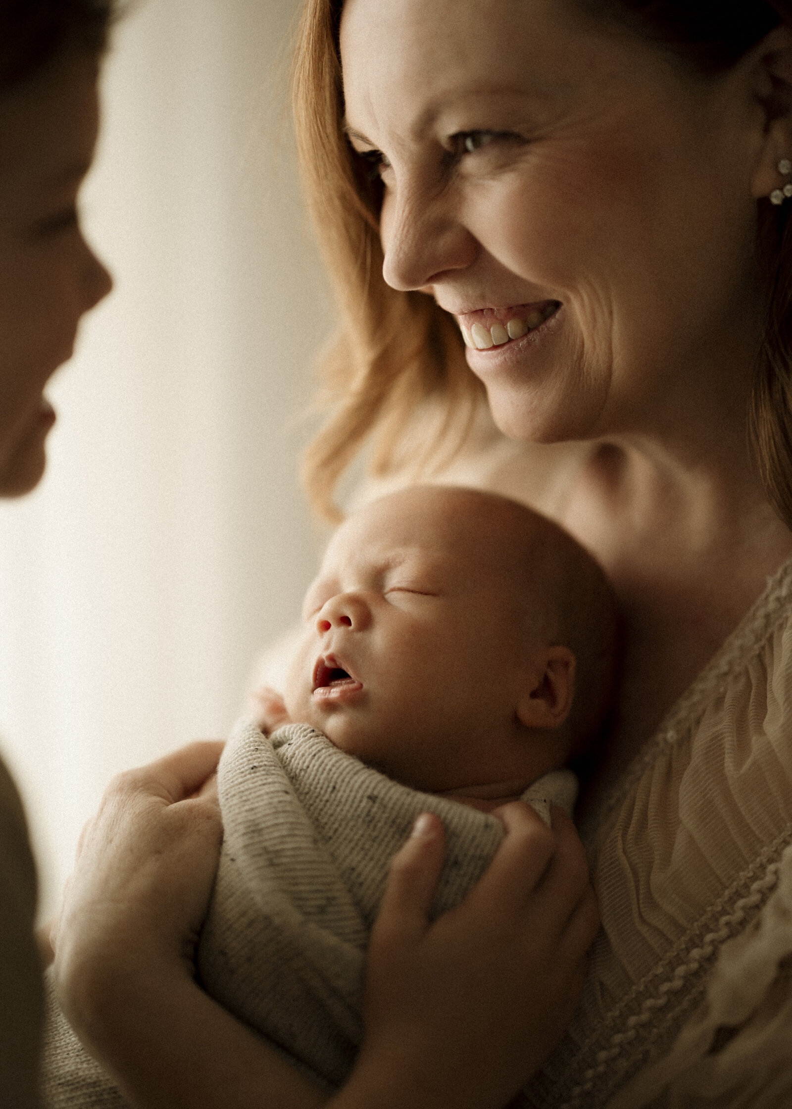 Studio newborn family photography in Perth – a beautiful, intimate portrait of new parents holding their baby in soft natural light.