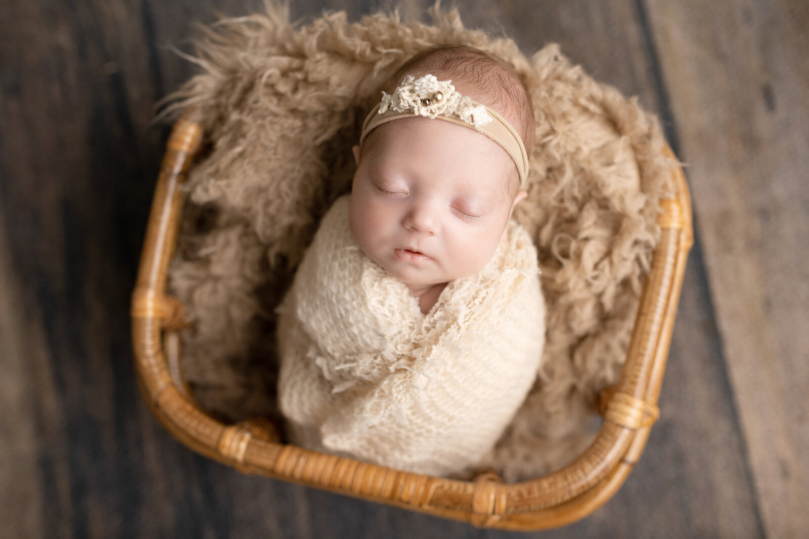 baby girl in cream wrap in a basket