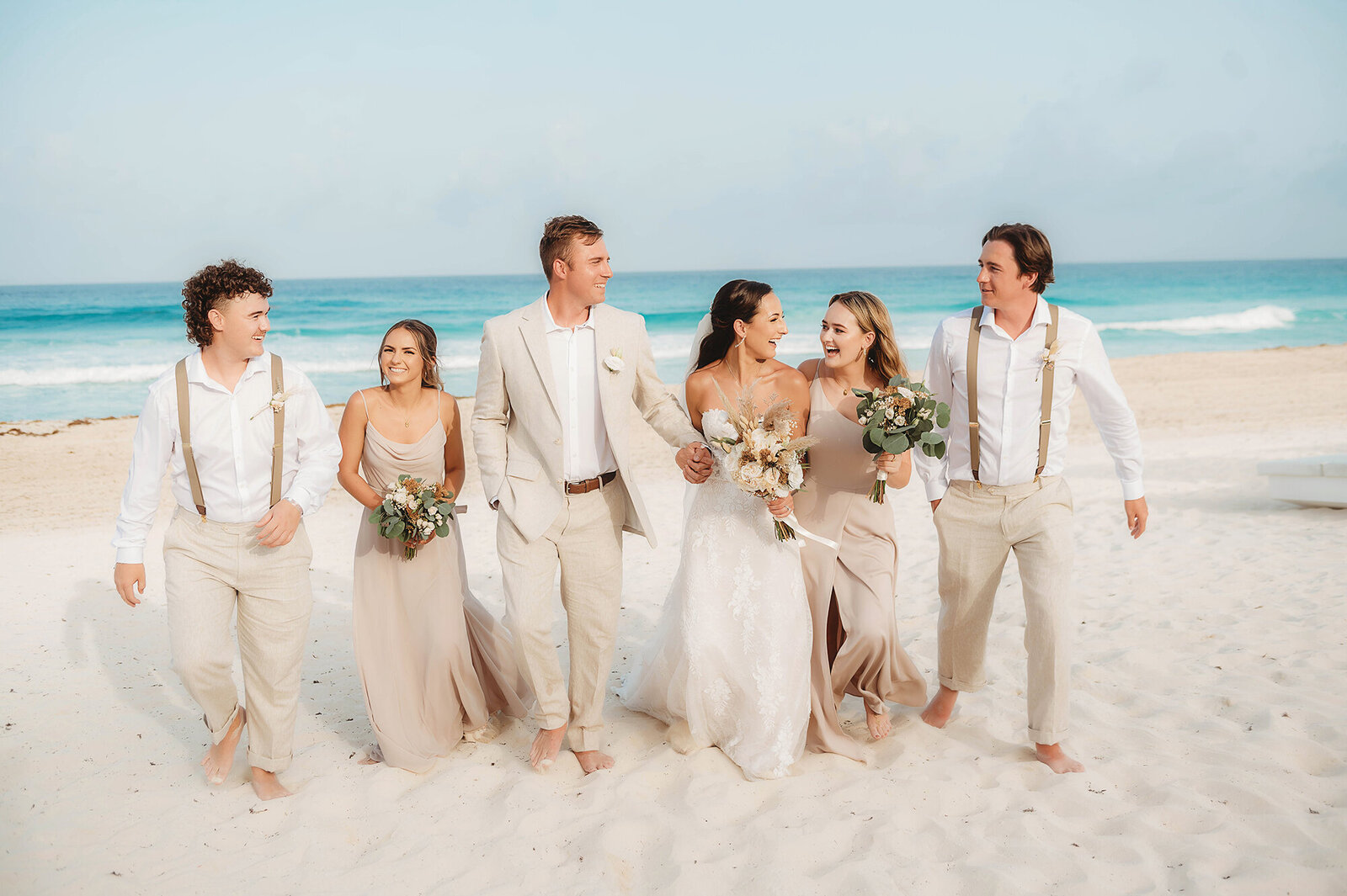 Bridal Party walks along the beach in Cancun Mexico.