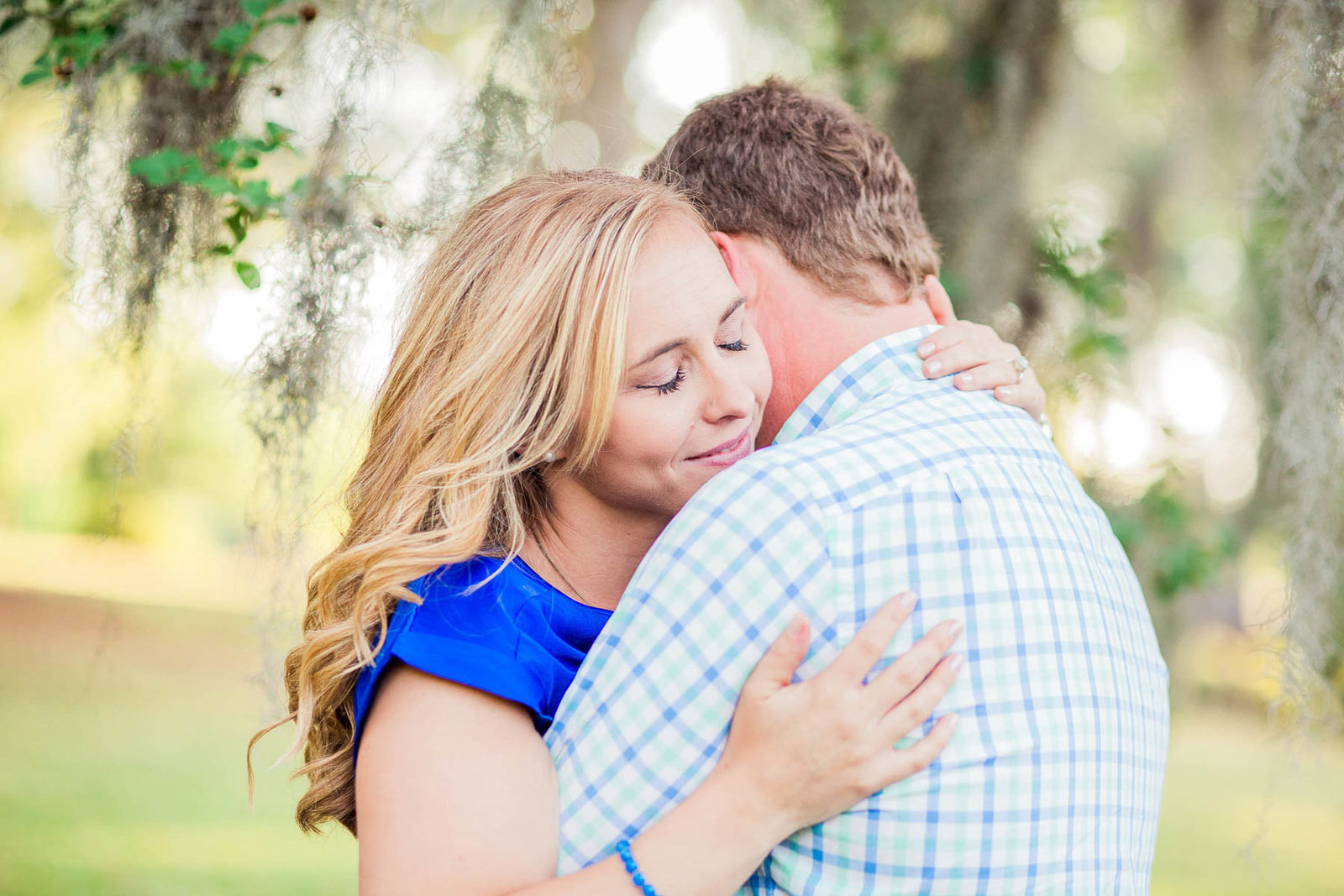 Engaged couple cuddle under a tree with spanish moss, Hampton Park, Charleston, South Carolina