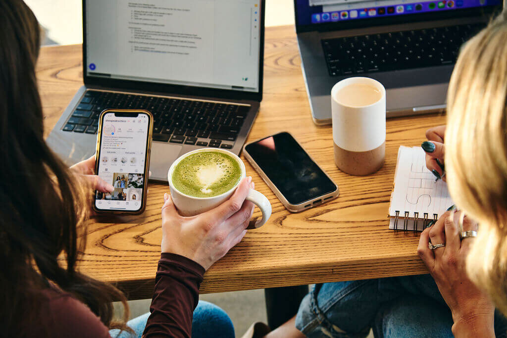 holding an iphone and writing in notebook