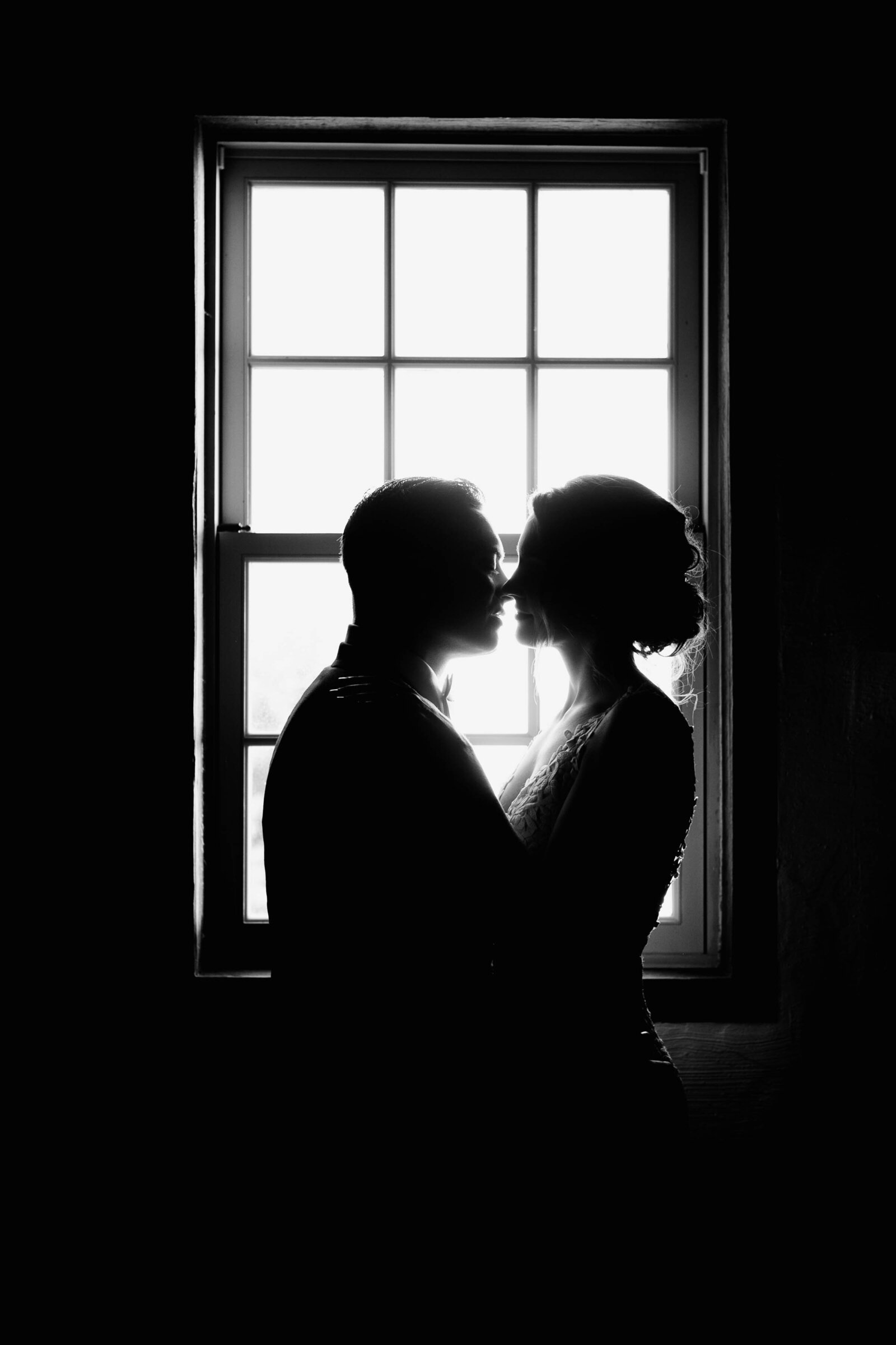 bride and groom in moody window light