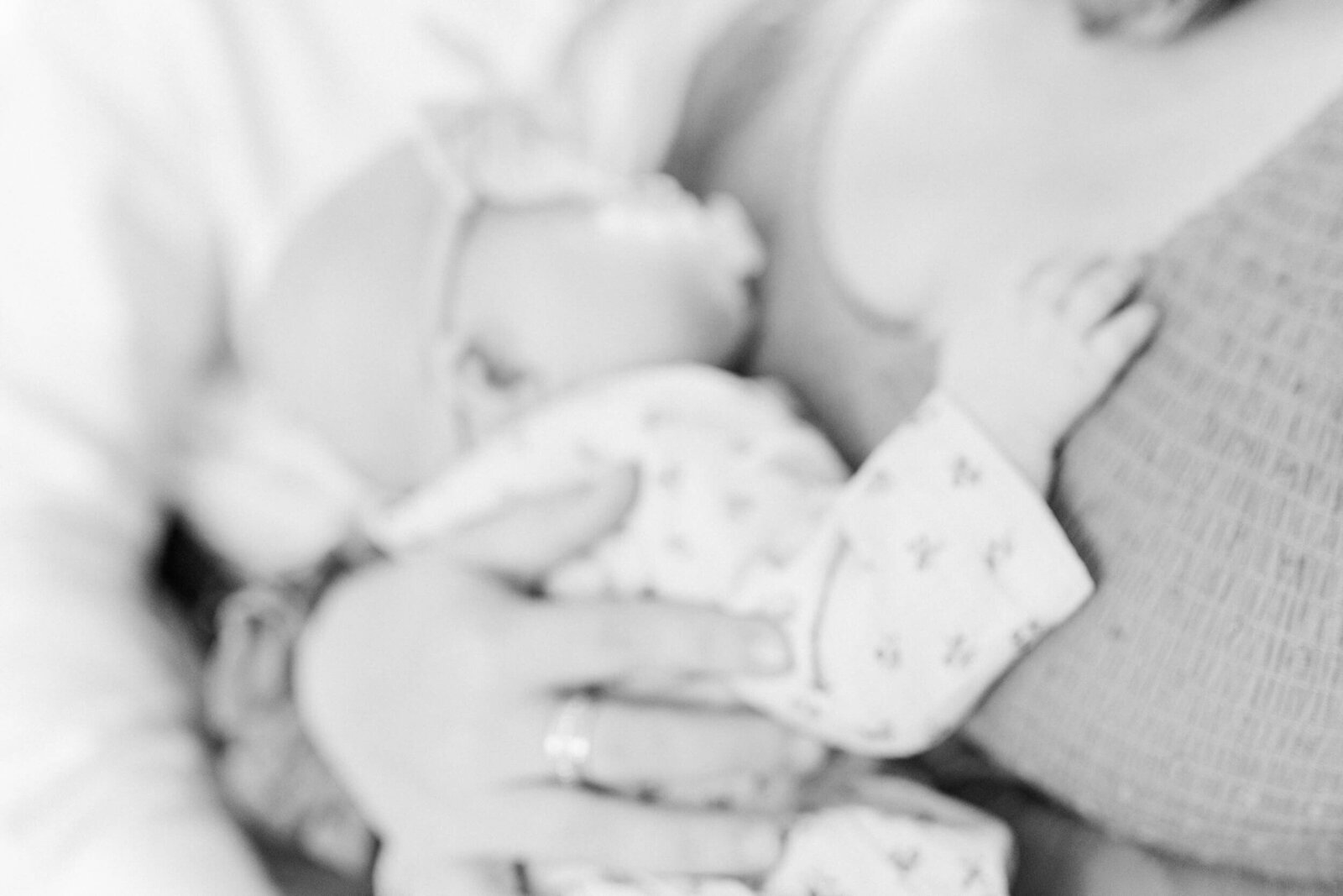 artistically soft focus, blurry black and white image of sleeping newborn's hand resting on mom's chest