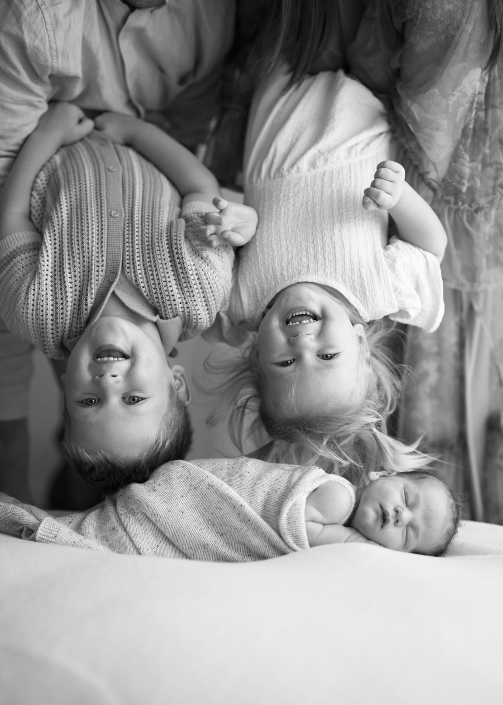 Best newborn family photographer in Perth capturing a tender moment between parents and their newborn in a cozy studio setting.