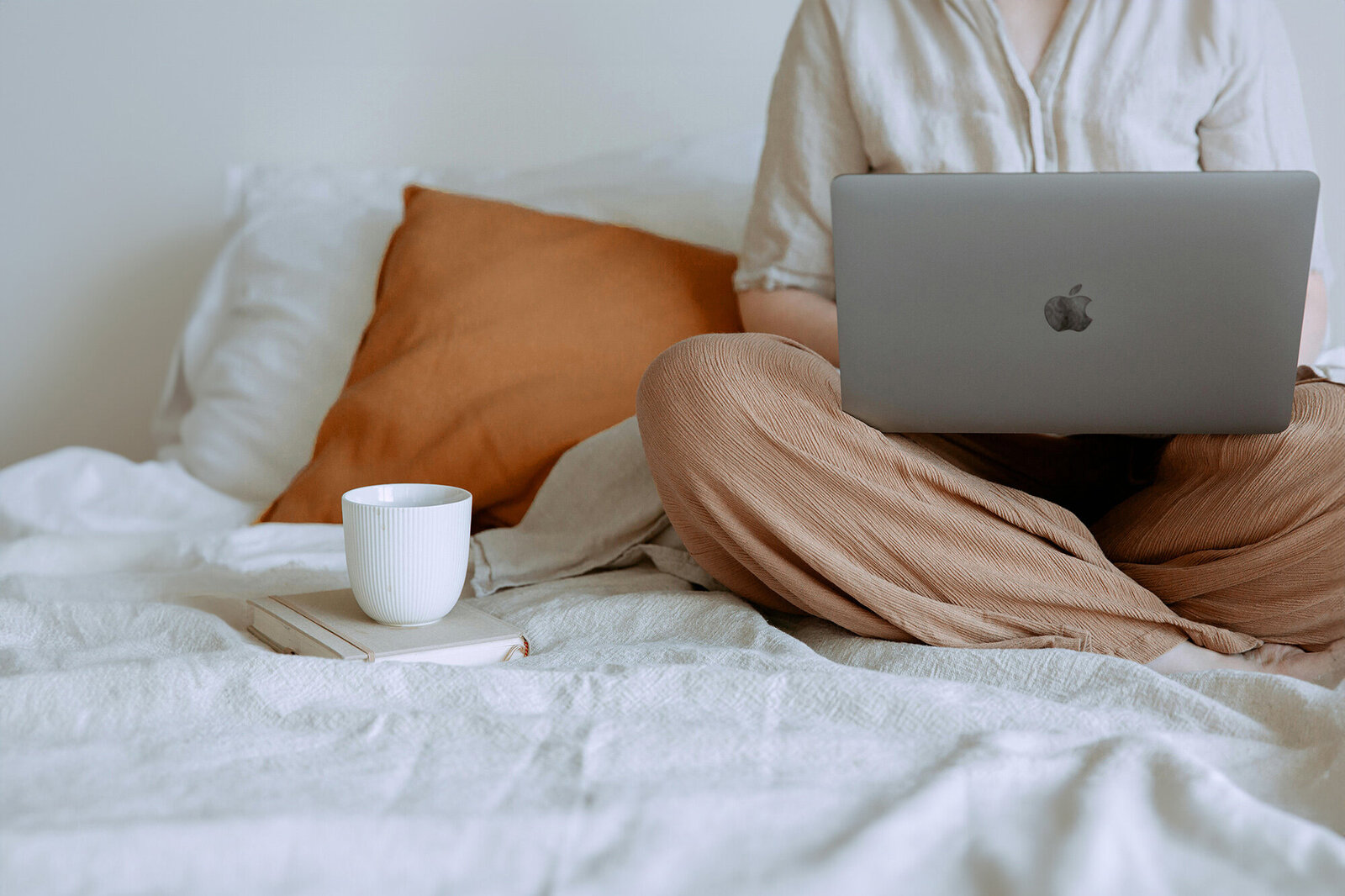 Woman sitting on bed using her Apple laptop for financial planning, symbolizing clarity and control over business finances. Take charge of your business finances with expert bookkeeping and strategic financial insights. Say goodbye to stress and hello to a streamlined, thriving business. Get started with your Financial Health Check-up Guide and build a stronger financial future today.
