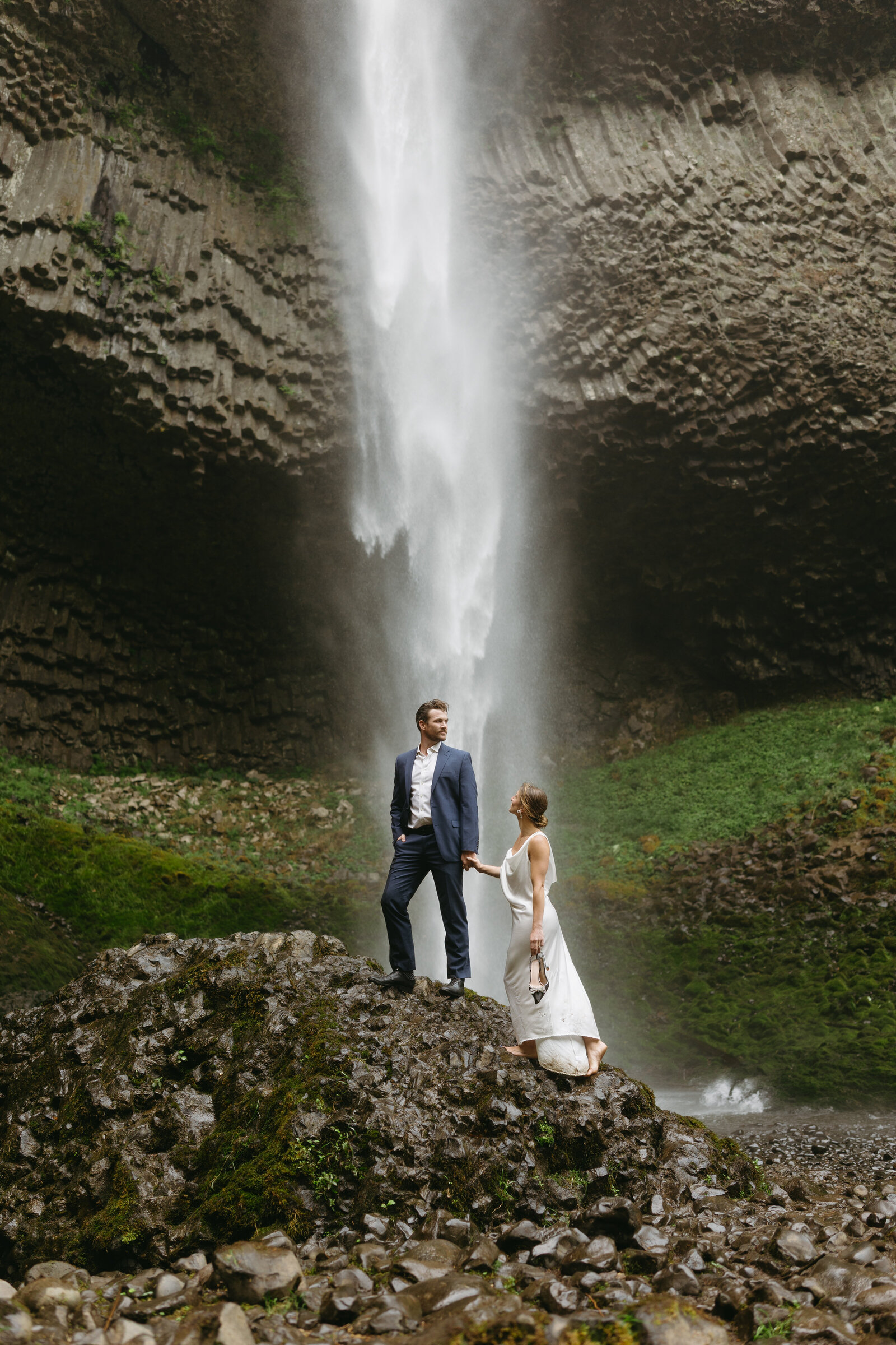 A bride and groom climb the rocks at a Nova Scotian waterfall after eloping. 