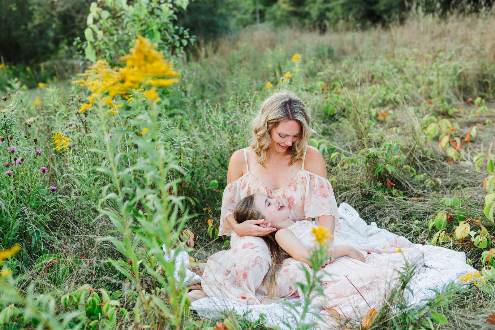 Mother and daughter lay and giggle in the tall grass in Guelph Ontario