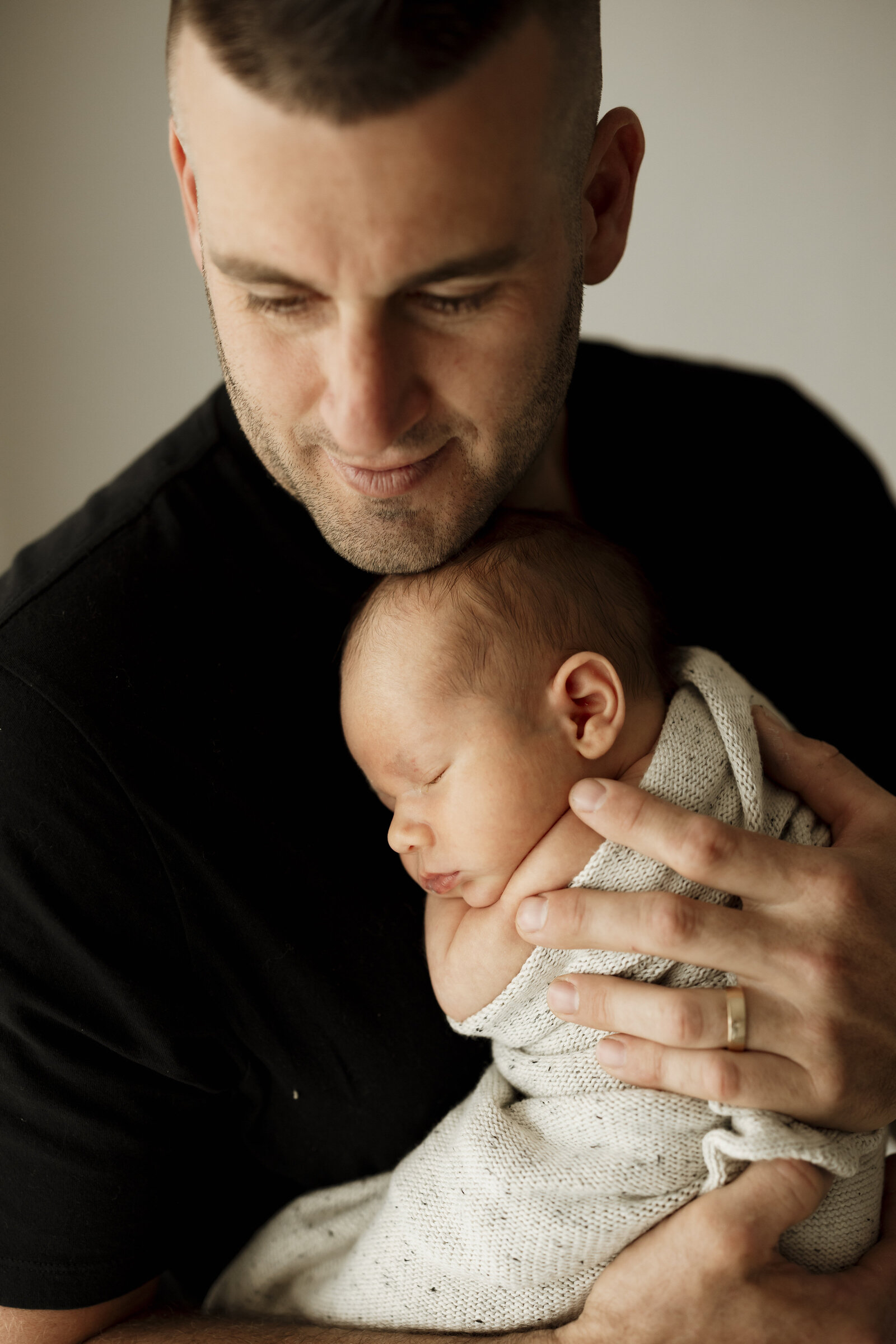 Studio newborn family photography in Perth – a beautiful, intimate portrait of new parents holding their baby in soft natural light.