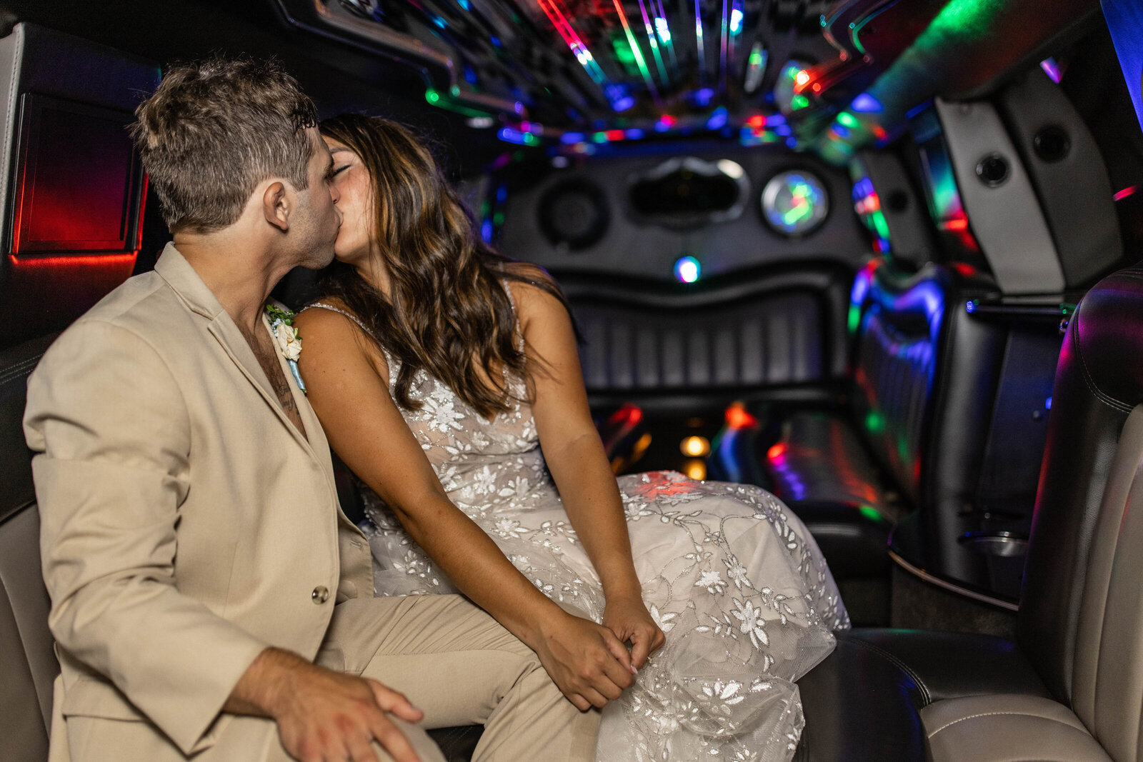 Groom and bride kissing in a limo as they leave form their wedding