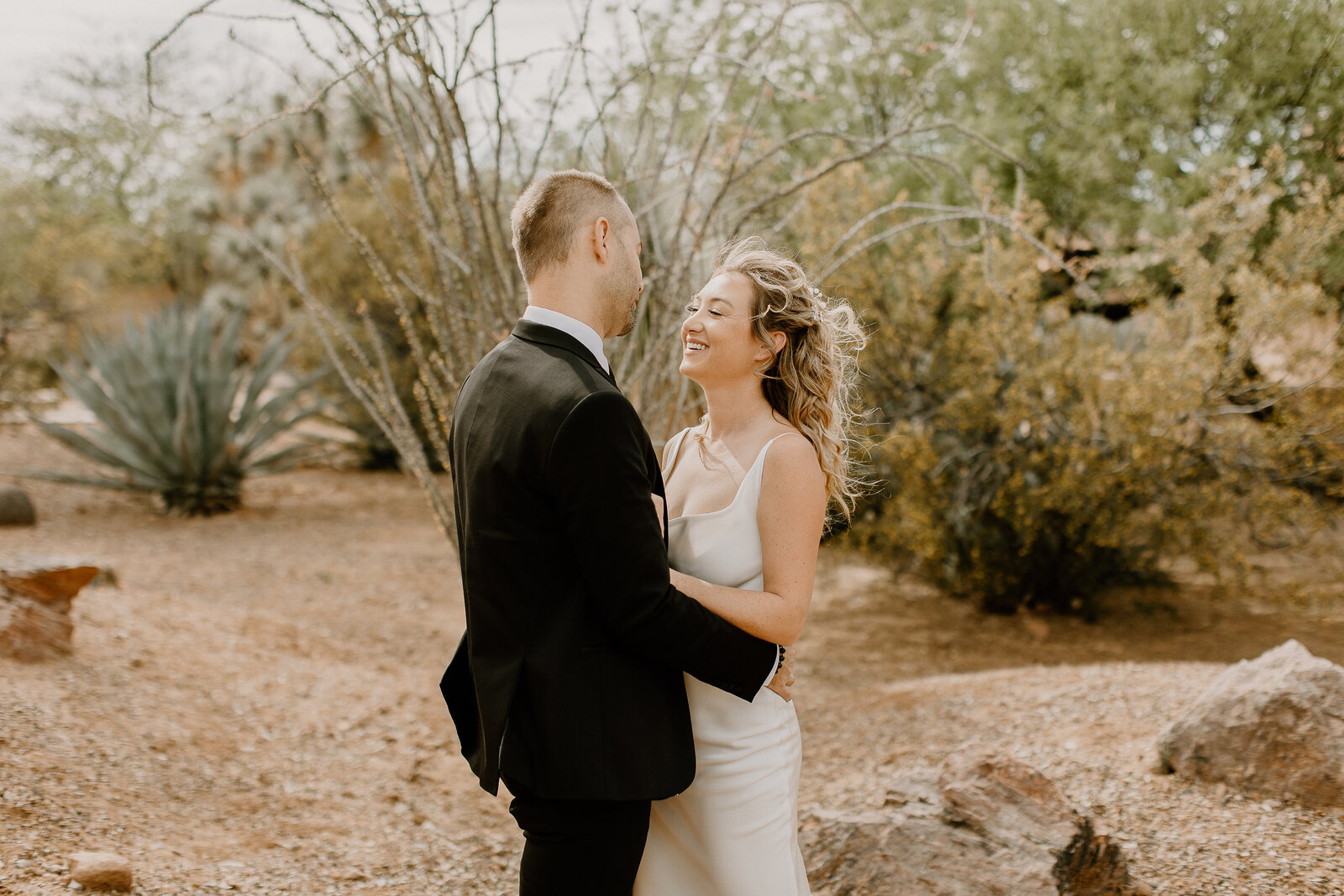 A couple with their arms around each other standing in a desert garden.