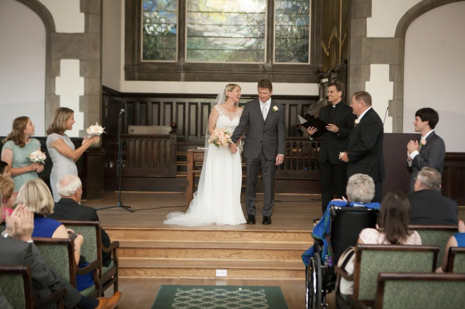 Bride and groom smile at each other holding hands as they walk down the aisle as a married couple