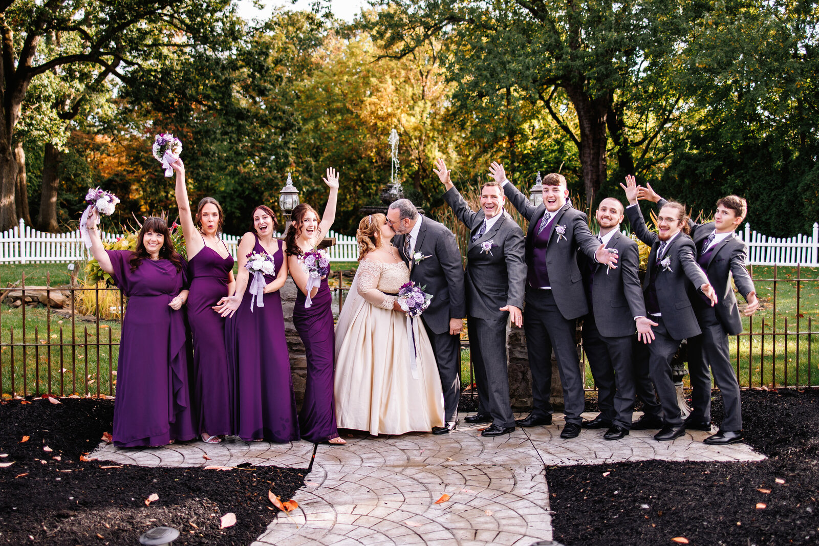 Bridal party cheers enthusiastically as bride and groom share a kiss
