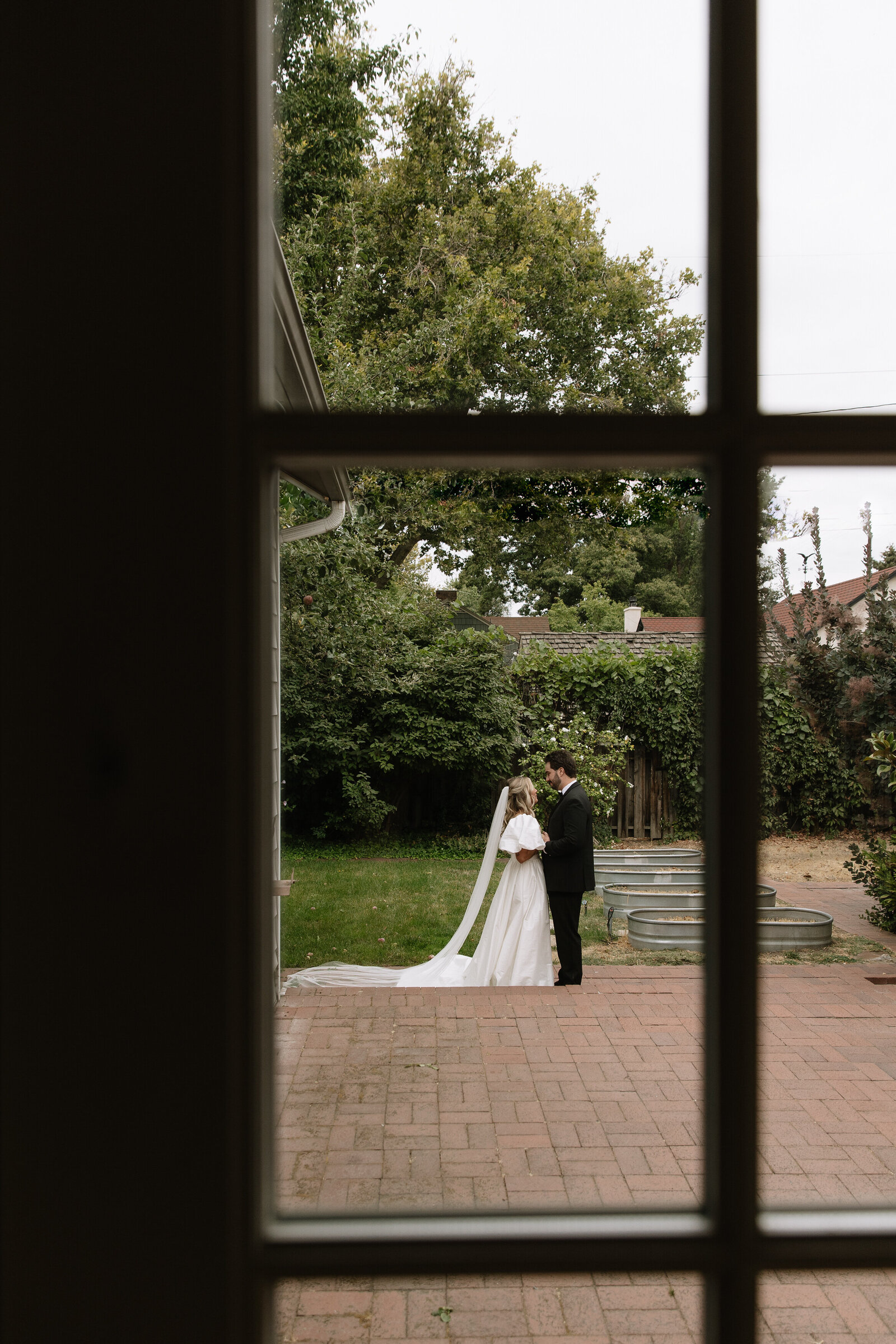 Photo of bride and groom sharing intimate moment through window of getting ready suite in Boise, Idaho