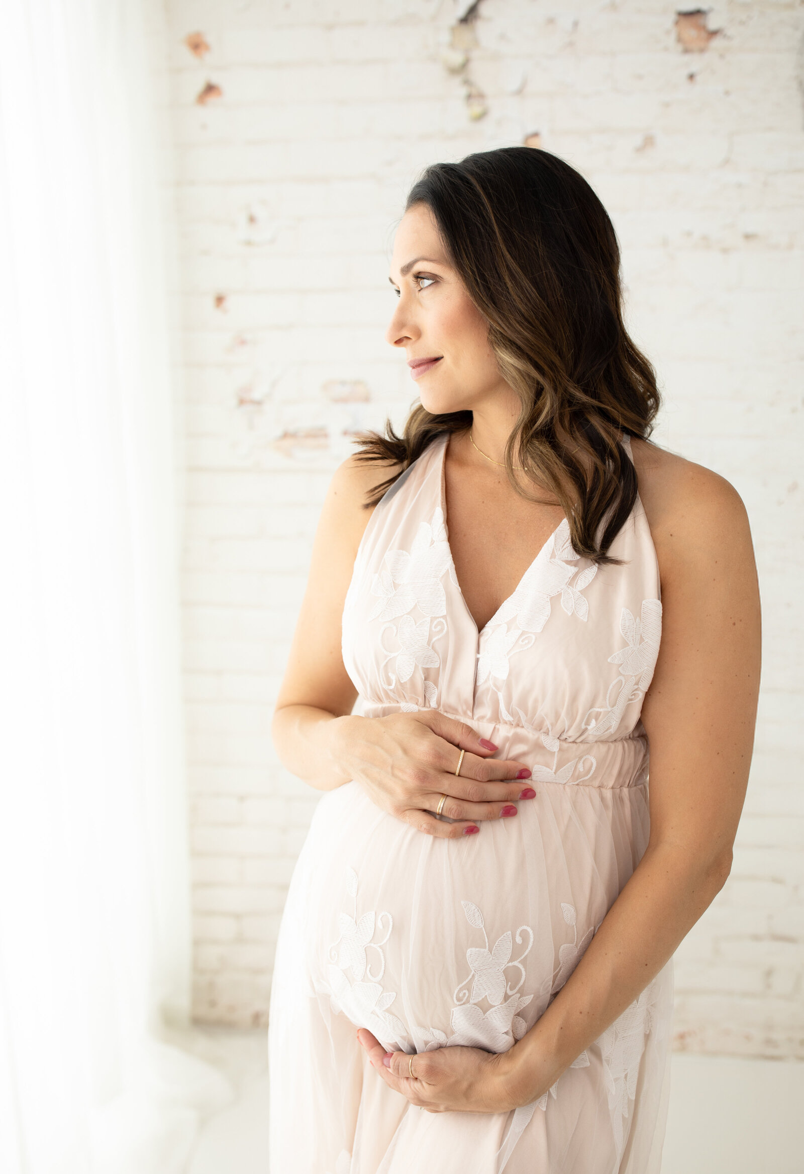 pregnant mother in maternity gown holding baby bump for photoshoot