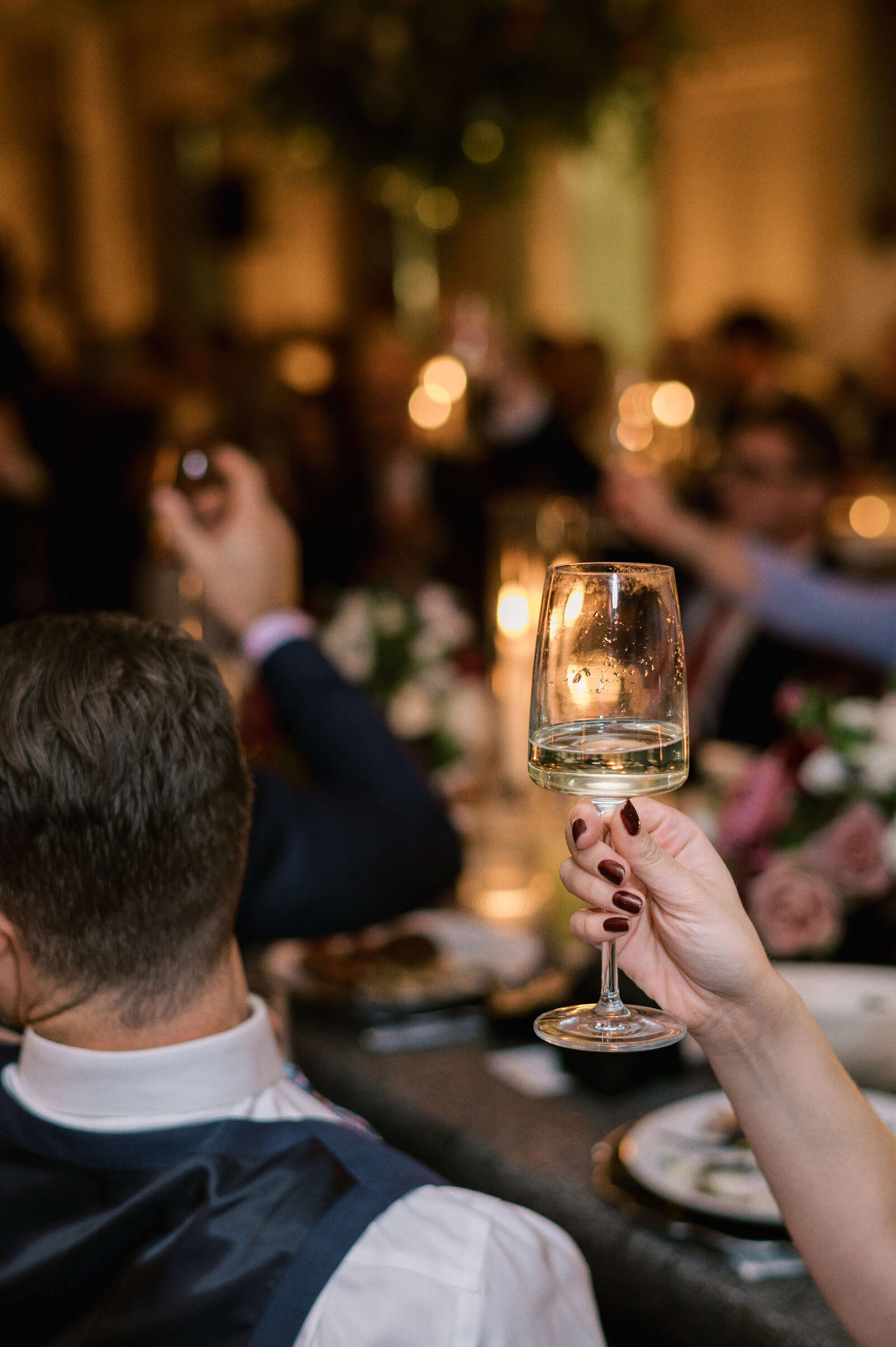A glass of wine is raised in toast at a Virginia wedding
