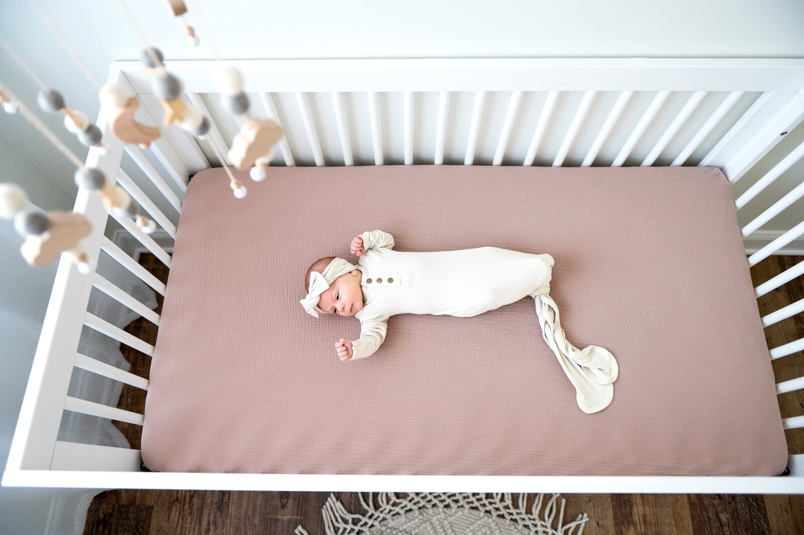 baby in a white outfit in her crib
