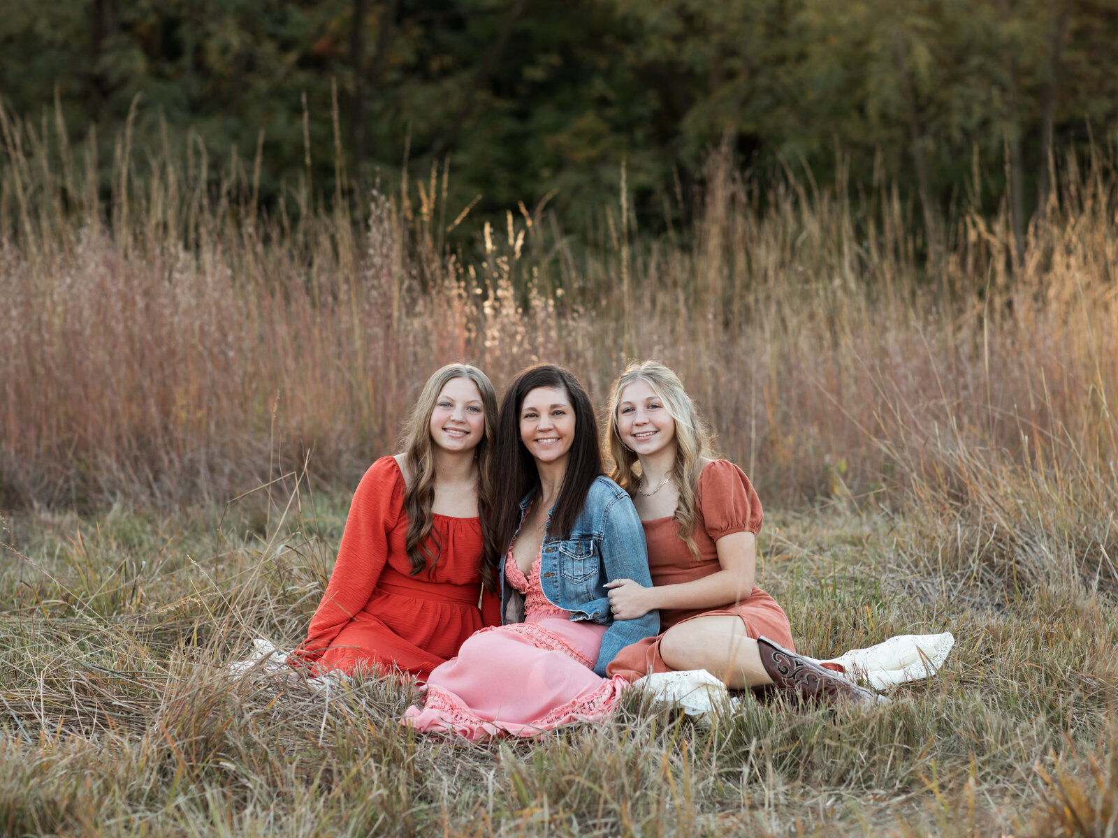 mom and two daughters sitting at park for family photos 