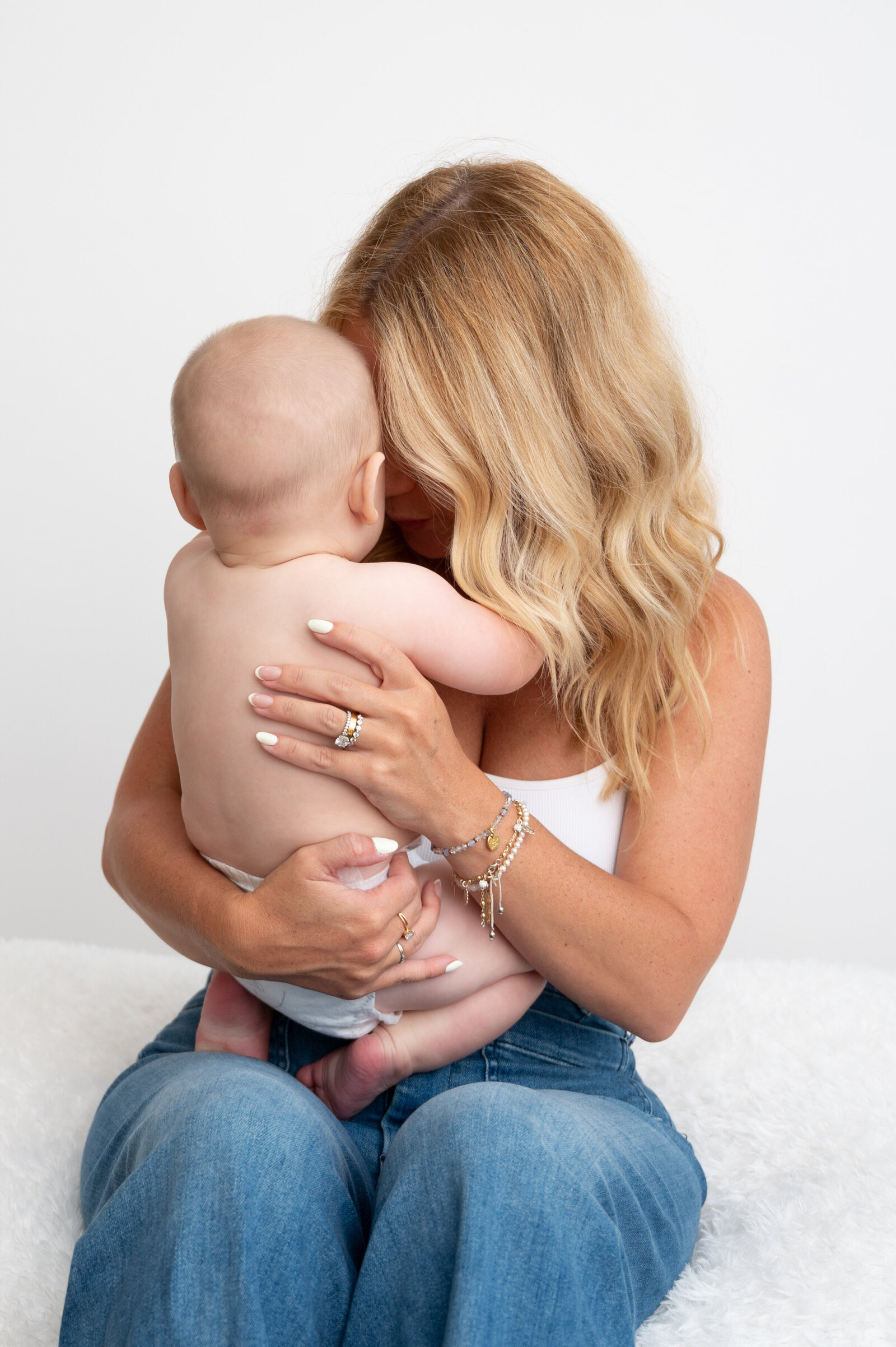 mom  in white and denim, baby in diaper looking at each other
