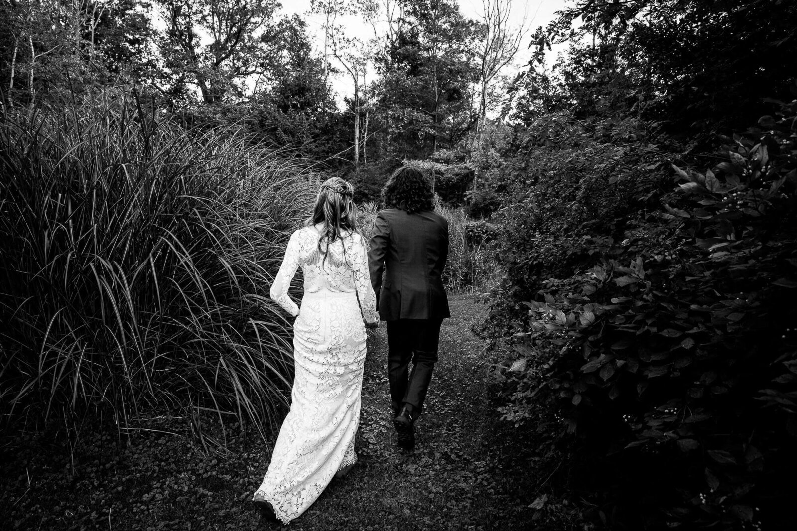 Black and white photo of bride and groom holding hands through wedding venue near London Ontario.