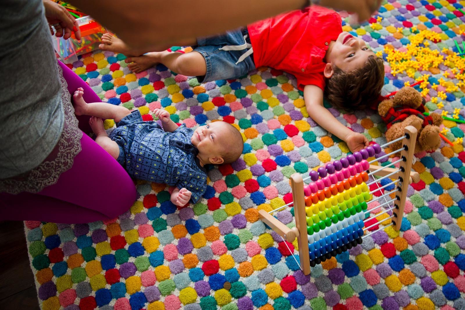 photo of baby and toddler brother laying on colorful rug