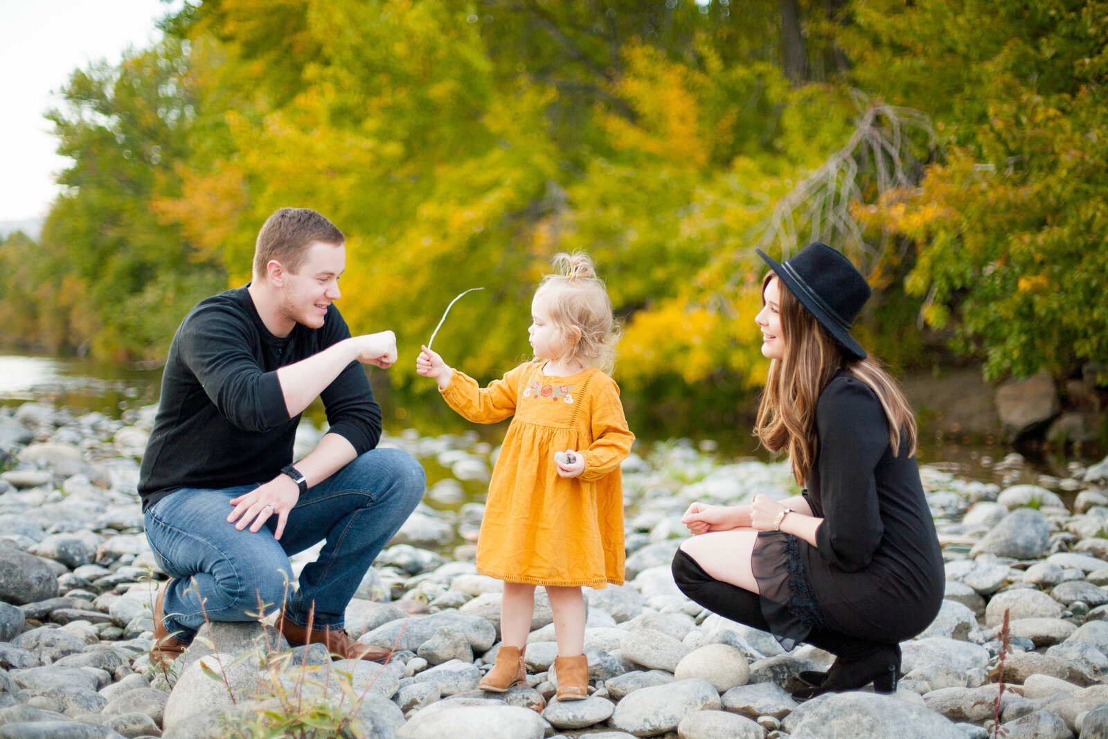 An child wearing a yellow dress playing with her parents.